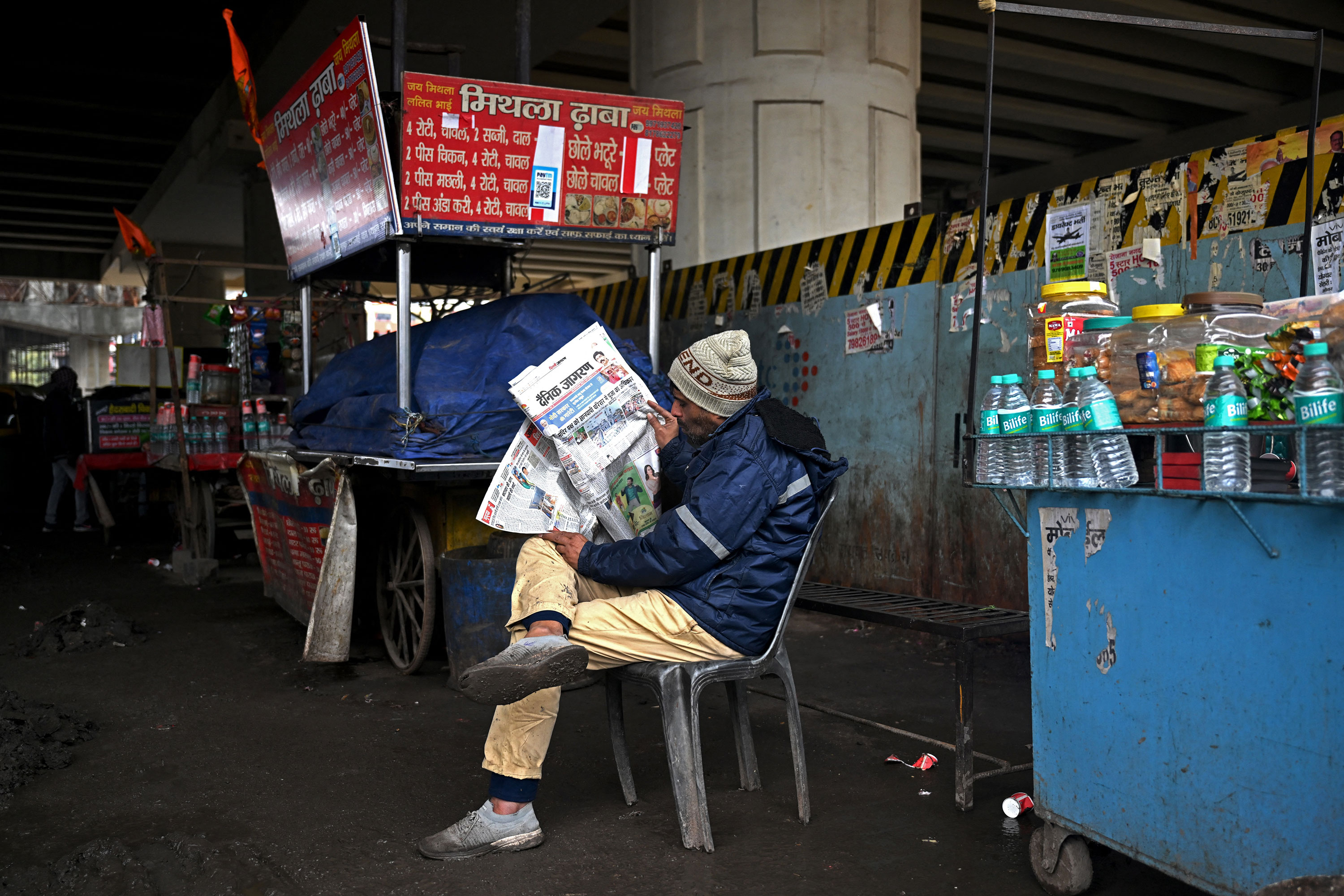 A vendor reads a newspaper next to his stall on a roadside in New Delhi on February 1. 