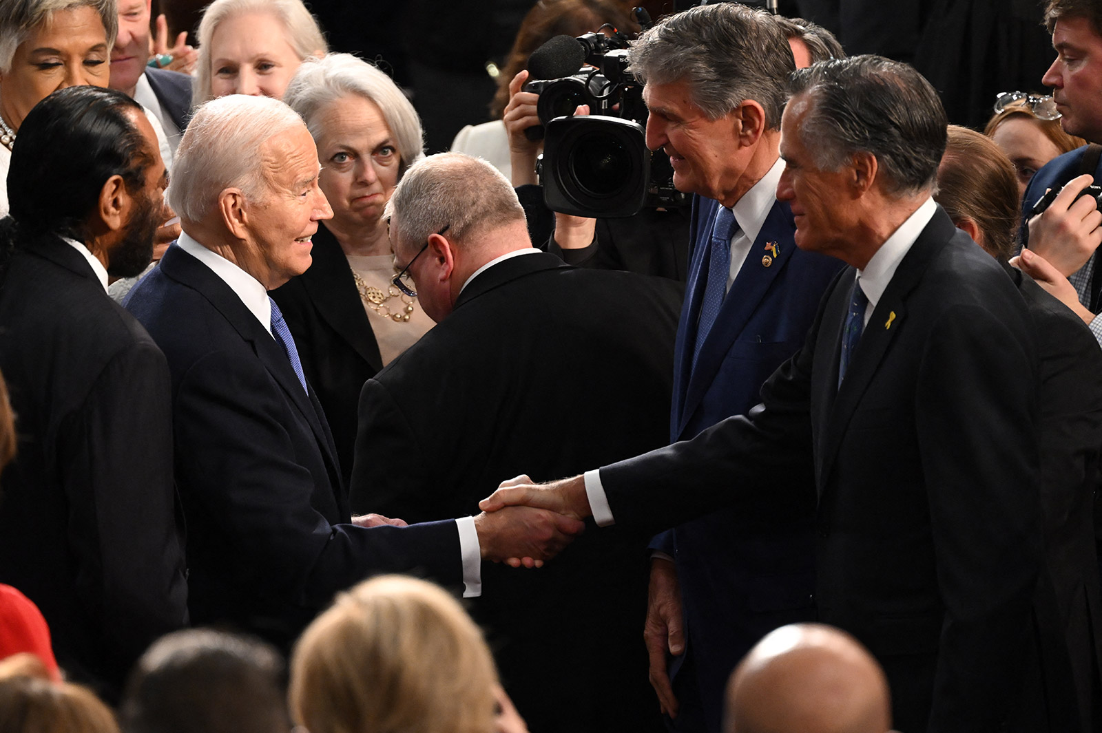 Biden speaks with Sen. Mitt Romney and Sen. Joe Manchin as he arrives in the House chamber.