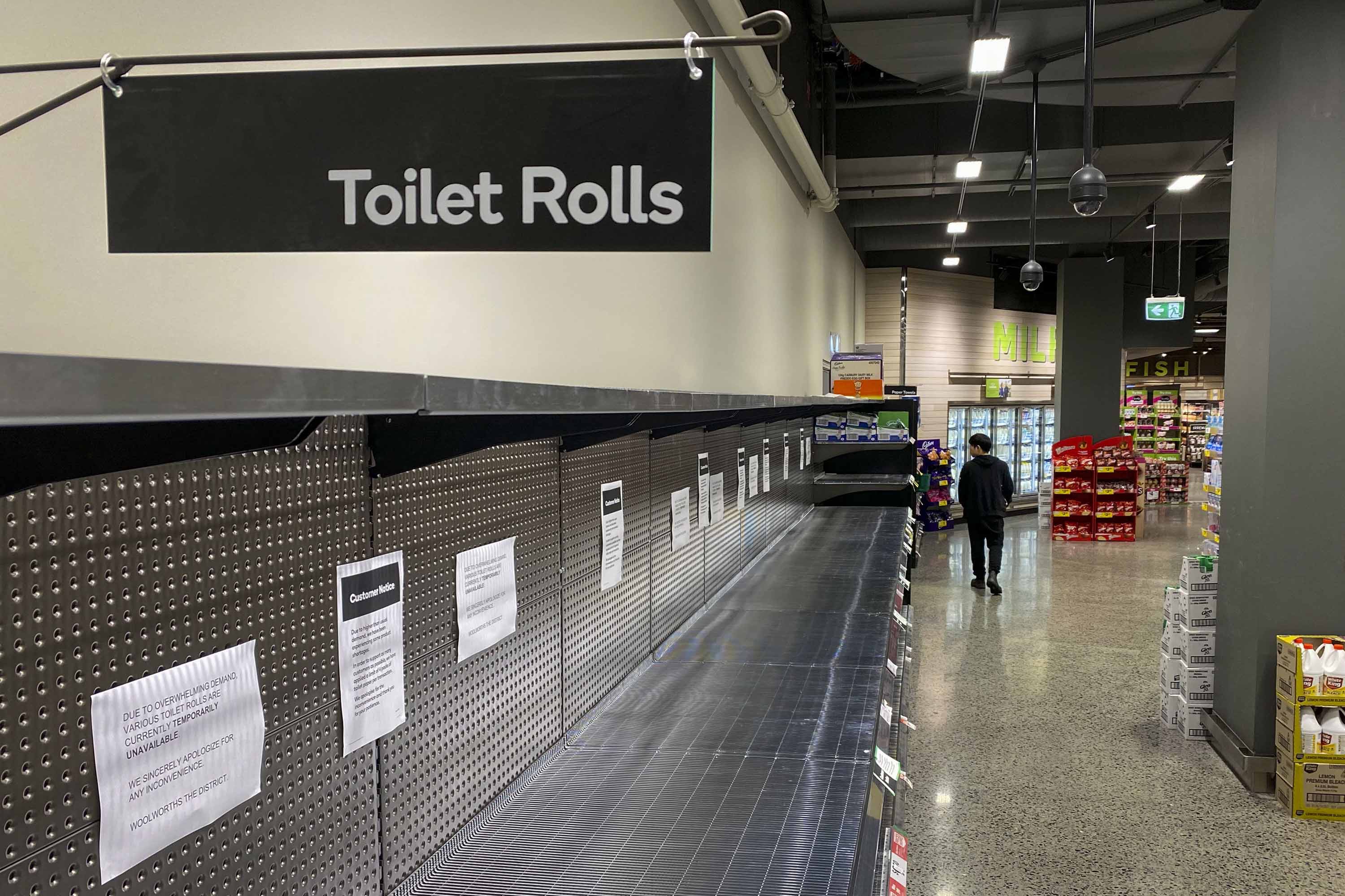 A shopper passes empty shelves usually stocked with toilet paper in a supermarket in Melbourne on March 5.