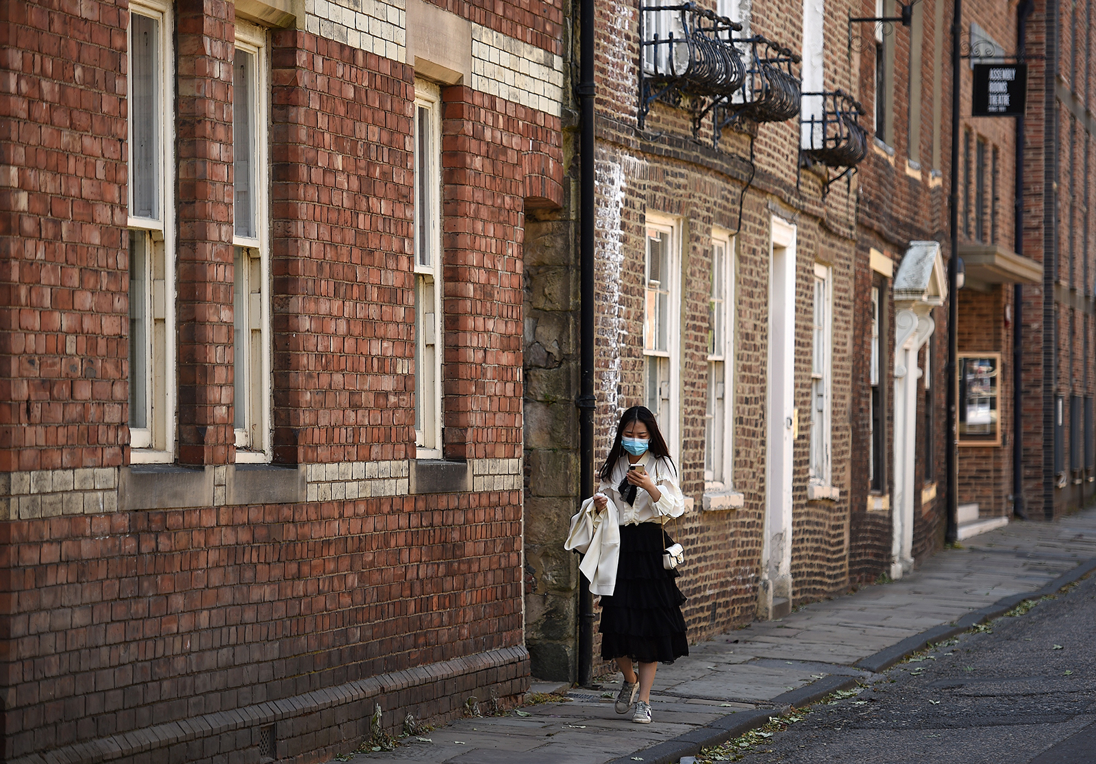 A woman wearing a face mask walks along a street in Durham, north east of England, on May 25.