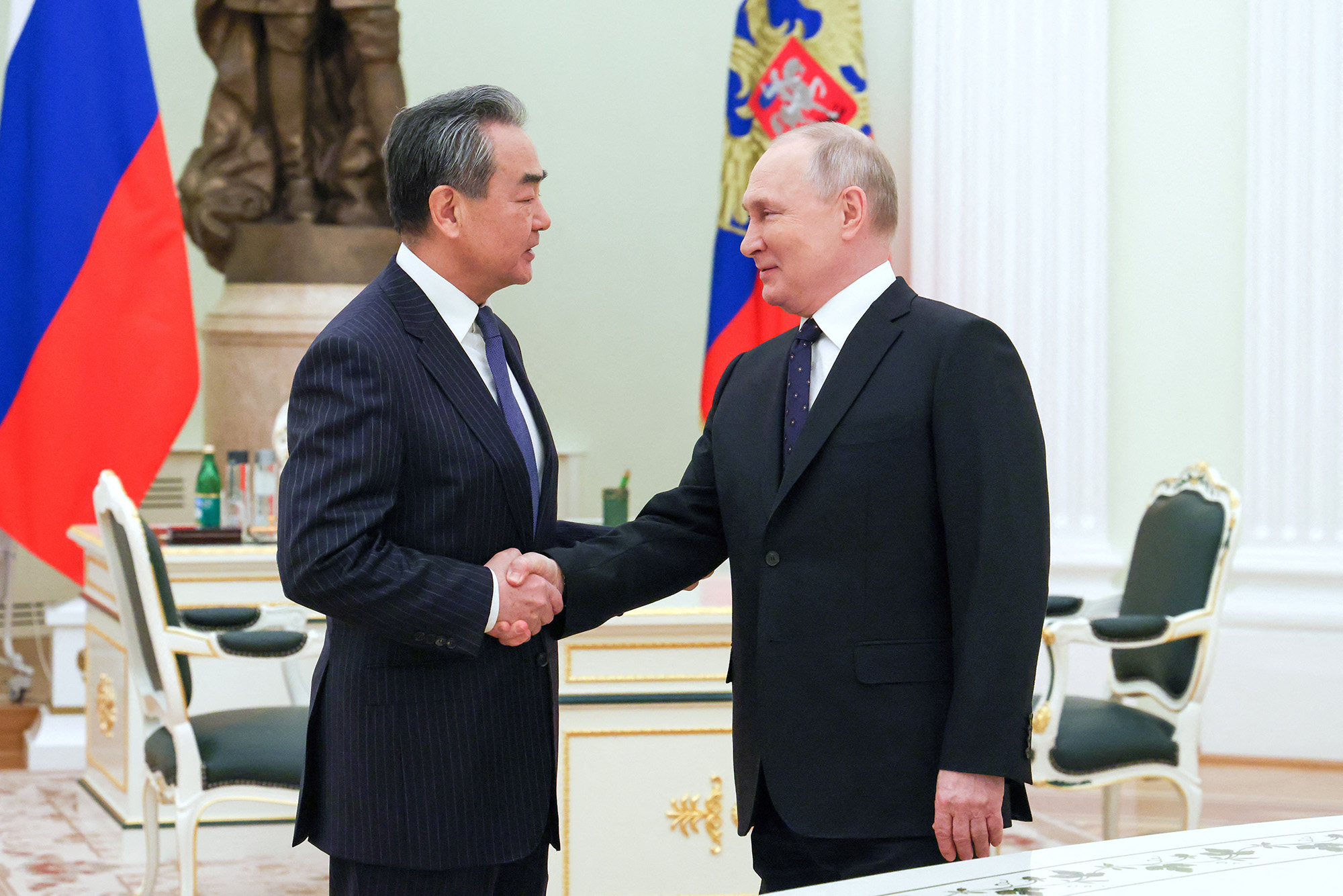 Russia's President Vladimir Putin, right, shakes hands with China's Director of the Office of the Central Foreign Affairs Commission Wang Yi during a meeting in Moscow, Russia, on February 22.