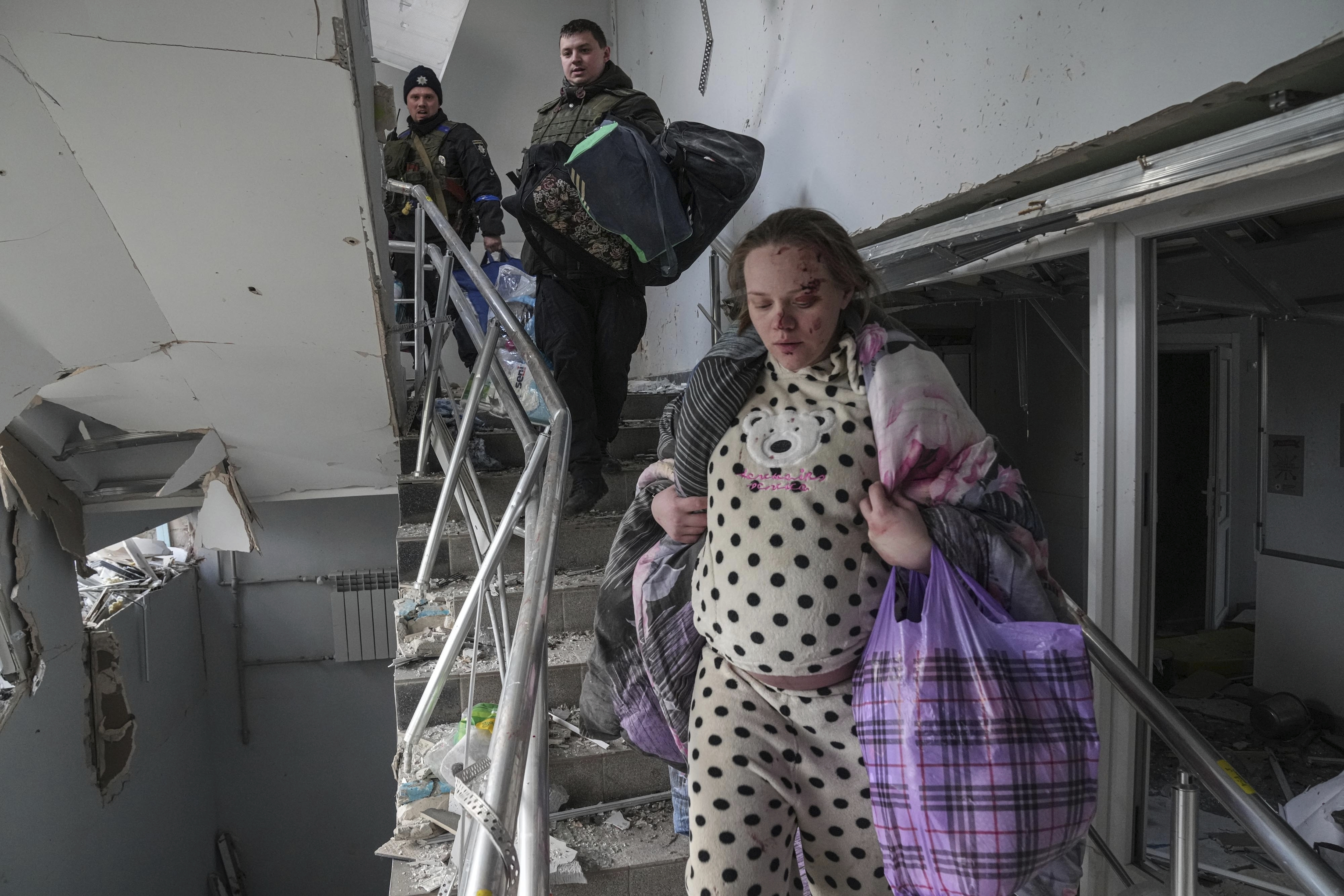 An injured pregnant woman walks downstairs in a maternity hospital damaged by shelling in Mariupol, Ukraine, on March 9.