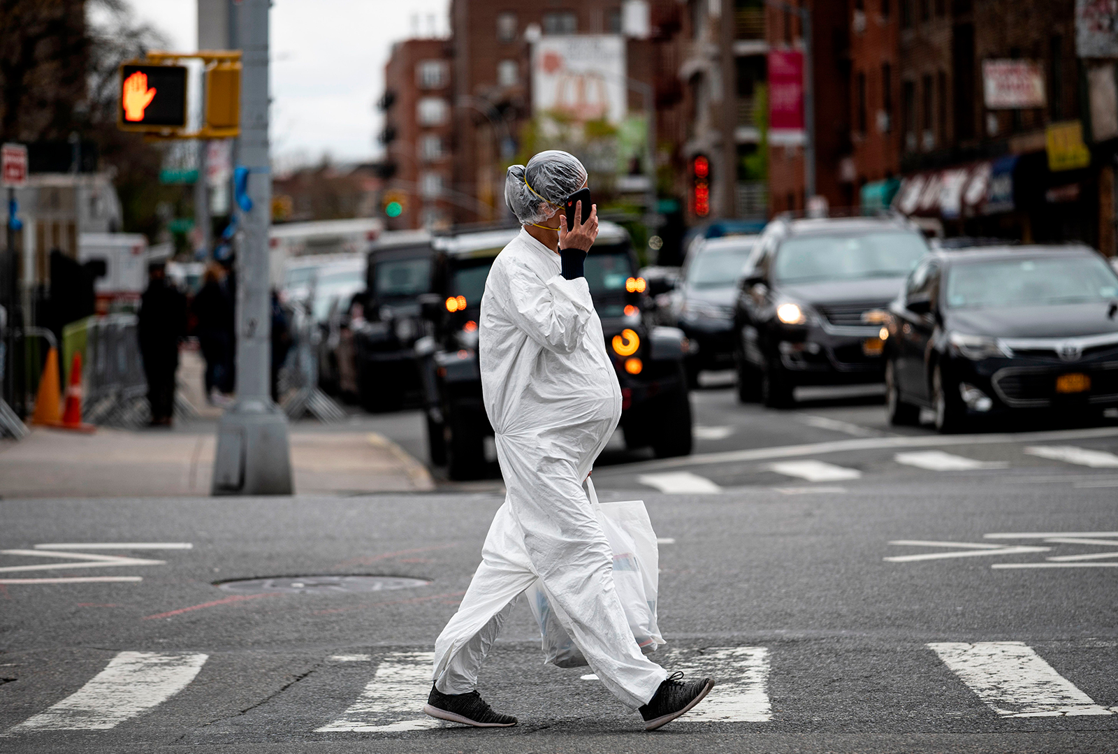 A pregnant woman wearing a hazmat suit and a mask walks in the streets in the Elmhurst neighborhood of Queens on April 27, in New York City.