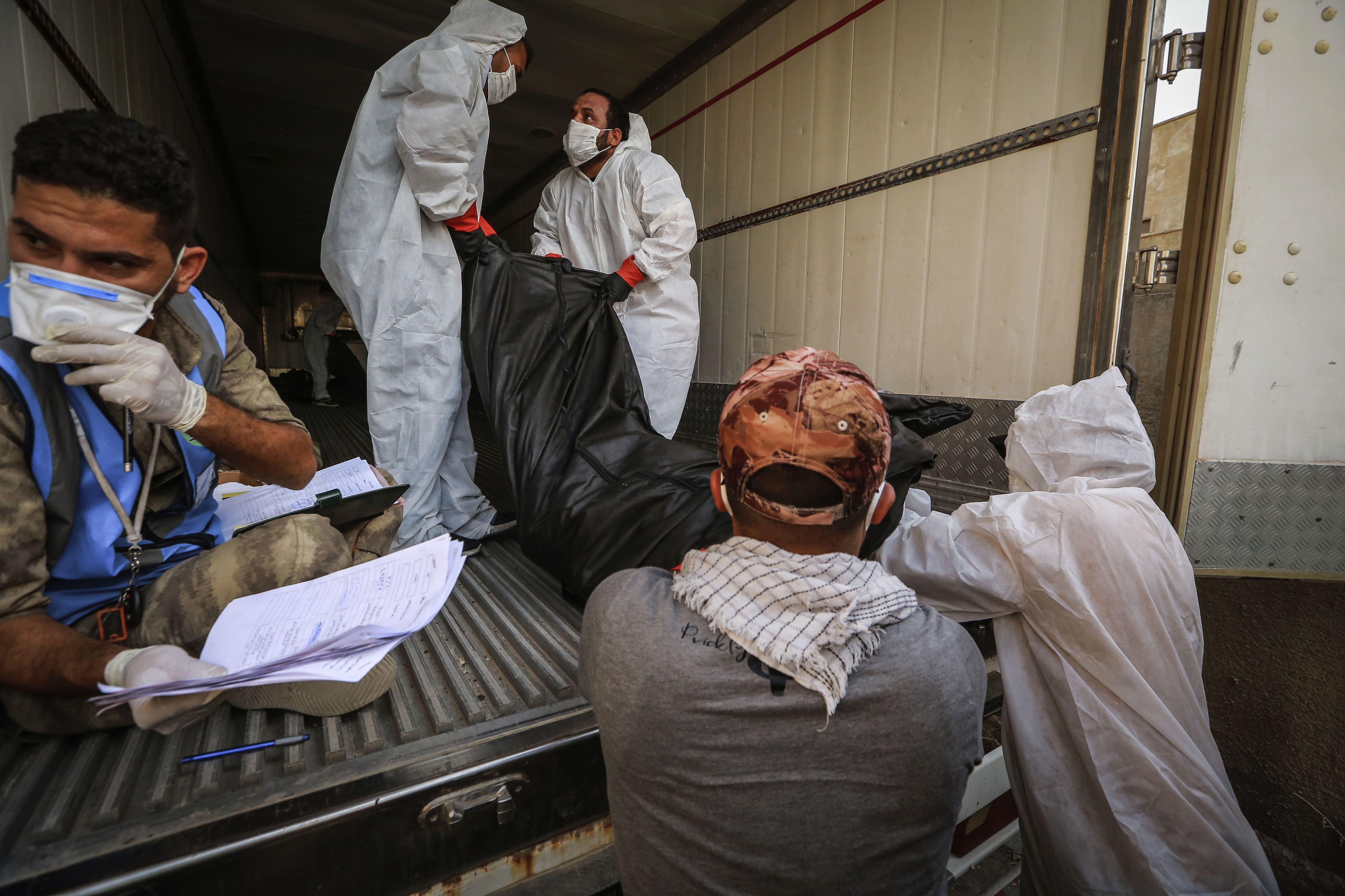 Workers in Baghdad, Iraq, put the body of a person said to have died from Covid-19 into a refrigerator truck to be transferred on July 11.