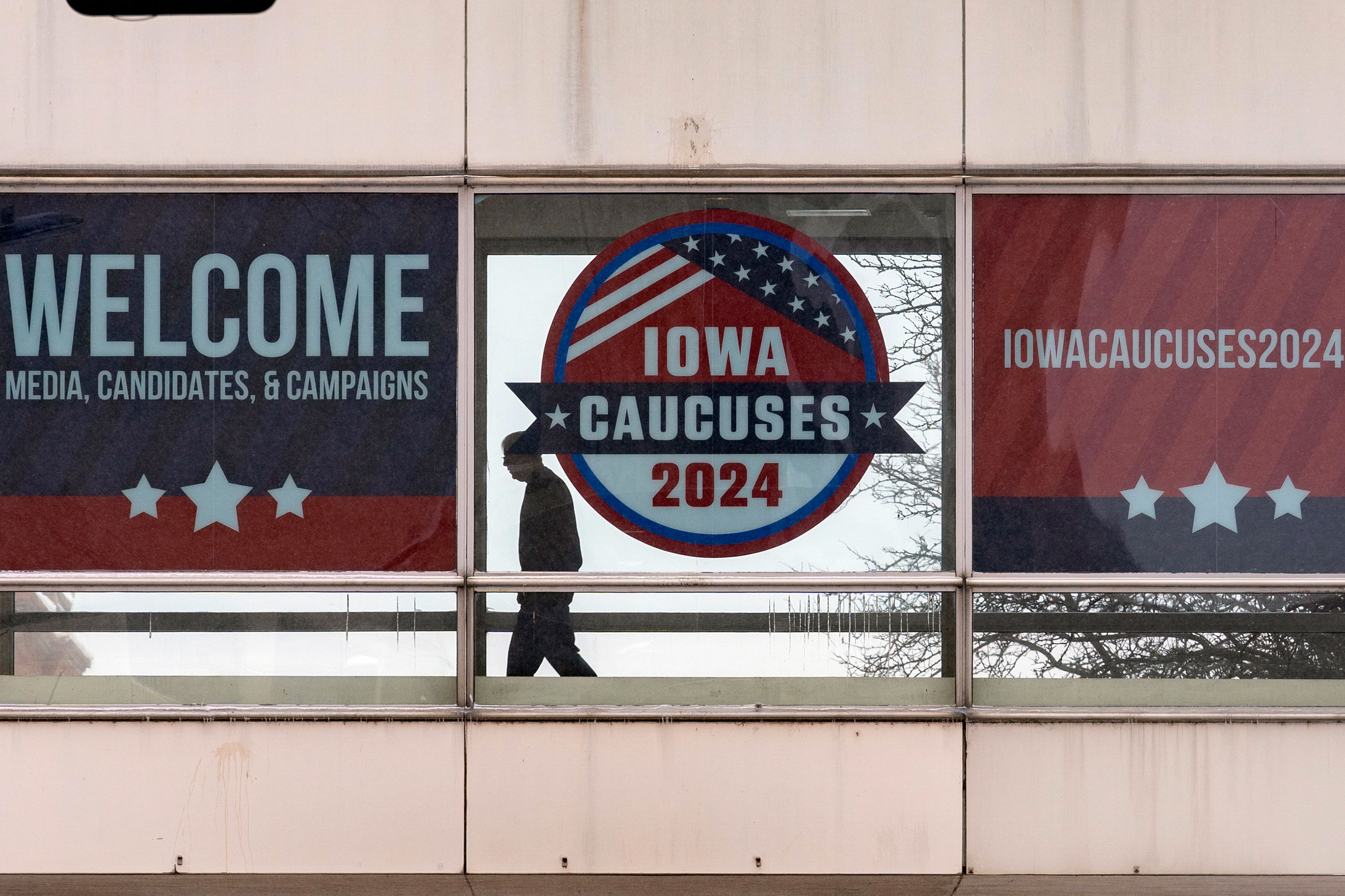A man walks past caucus signs in downtown Des Moines, Iowa, on Saturday.