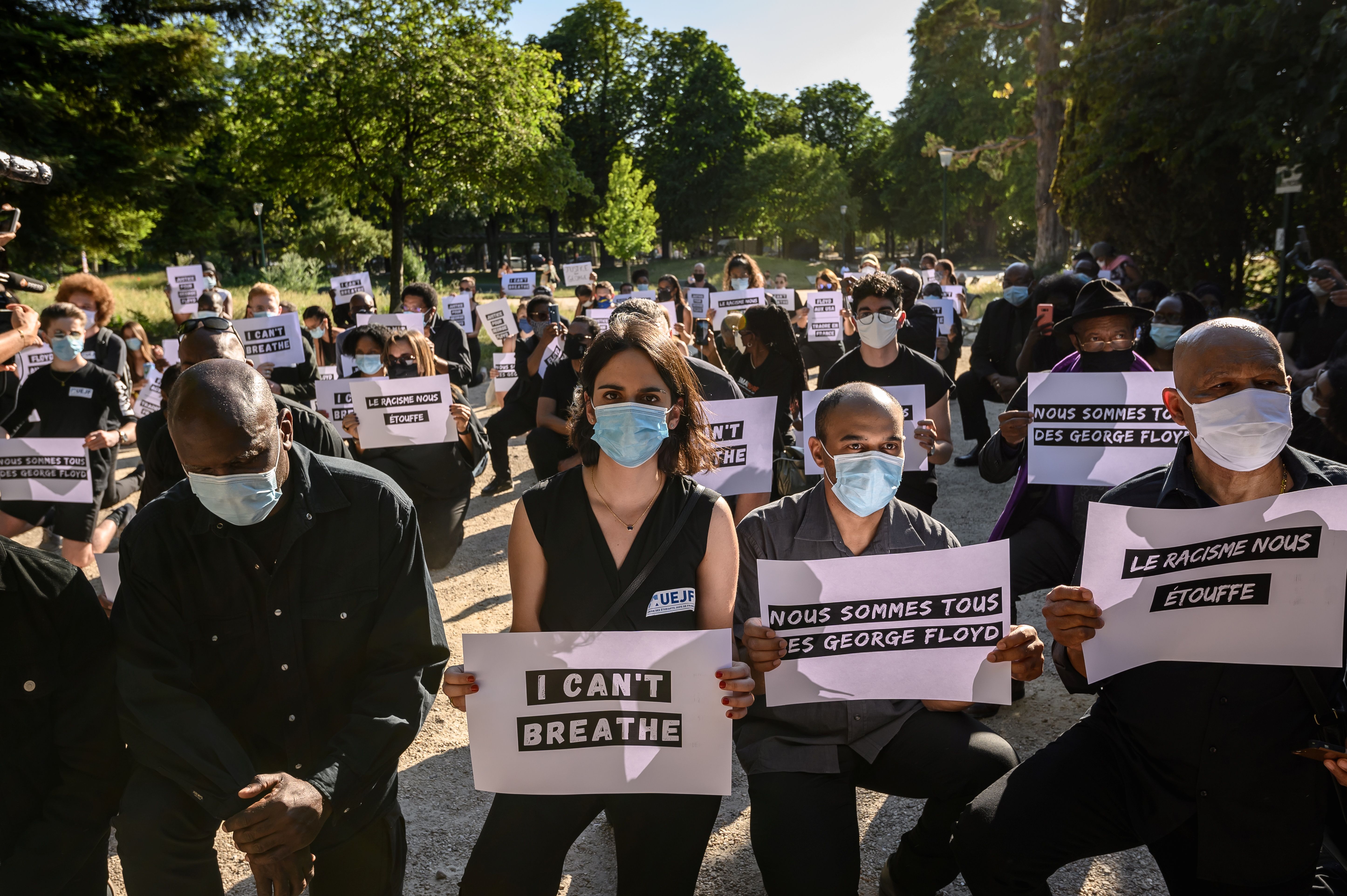 Protesters hold placards — including two reading "we are all George Floyd" and "racism is suffocating us" — during a demonstration outside the United States Embassy in Paris on June 1.