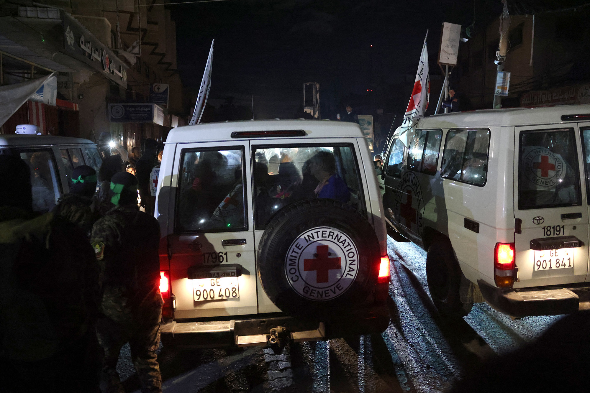 Hamas and Islamic Jihad fighters stand guard as Red Cross vehicles transport released hostages toward the Rafah border crossing with Egypt on November 28.