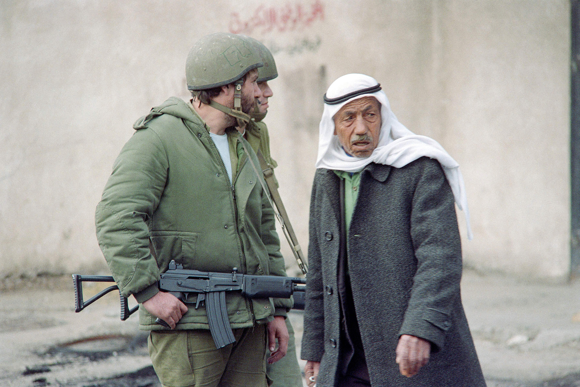 A Palestinian man passes Israeli soldiers patrolling in a street in Gaza on December 20, 1987.