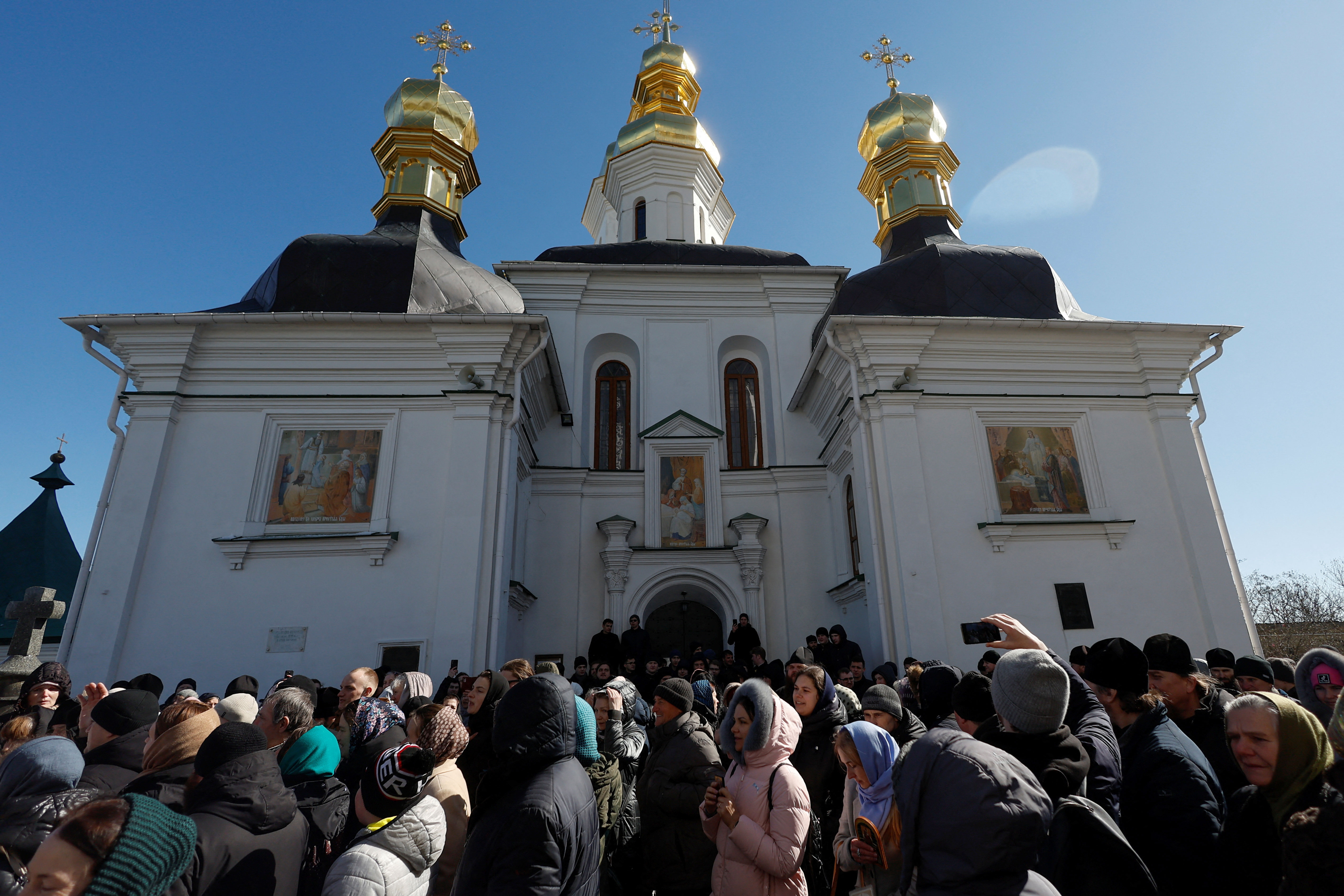 Believers of the Ukrainian Orthodox Church pray blocking an entrance to a church at a compound of the Kyiv-Pechersk Lavra monastery in Kyiv on March 30. 