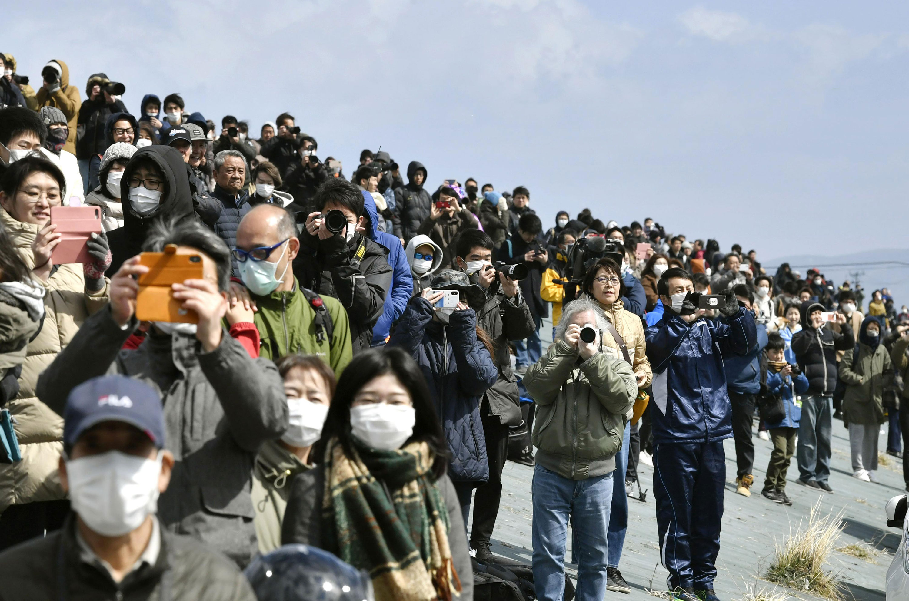 People watch the Japanese Air Self-Defense Force's Blue Impulse aerobatics team in Higashimatsushima, Miyagi, on March 20, where the Olympic flame arrived from Greece.