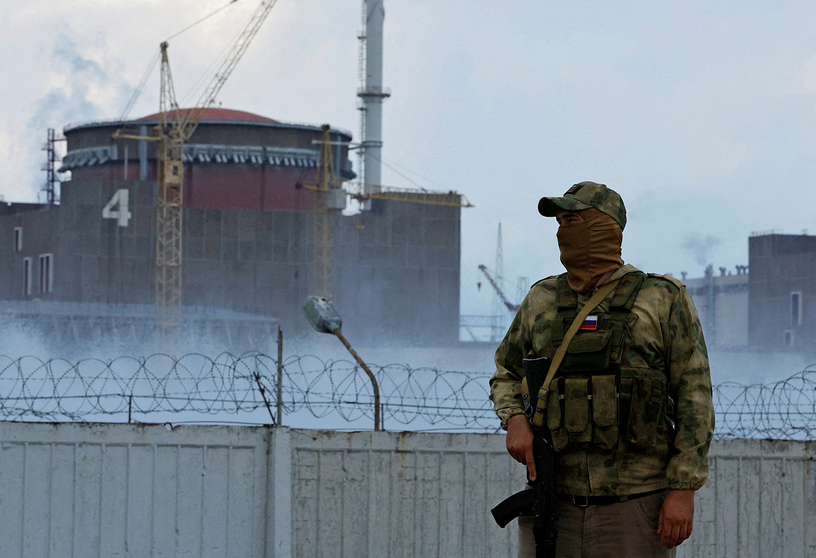 A serviceman with a Russian flag on his uniform stands guard near the Zaporizhzhia Nuclear Power Plant, outside the Russian-controlled city of Enerhodar, Ukraine, on August 4.
