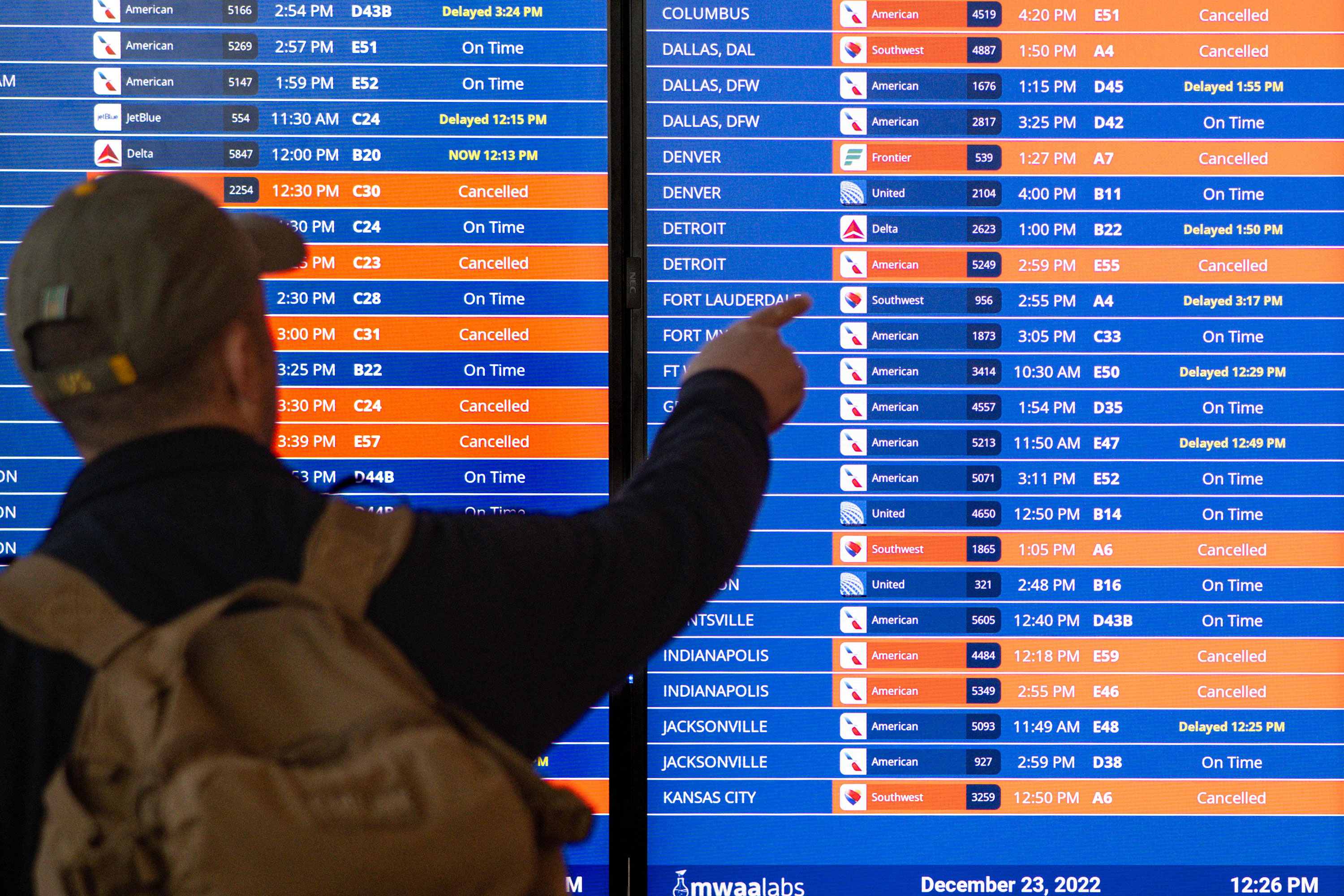 Travelers look at an information board showing flight cancellations and delays at Ronald Reagan Washington National Airport in Arlington, Virginia, on Friday.