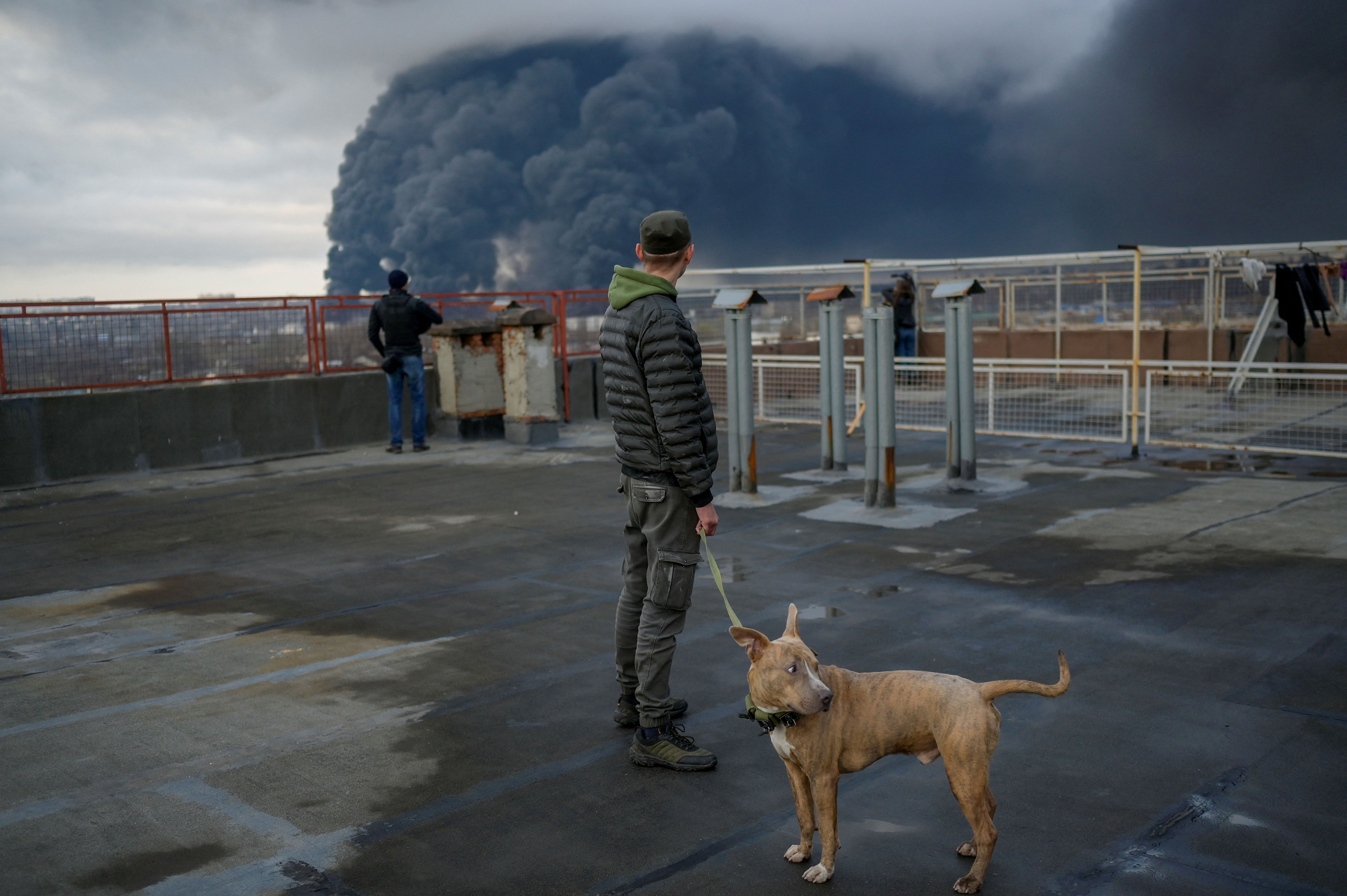 A man stands with his dog as smoke rises after a Russian attack in Odesa, on April 3.