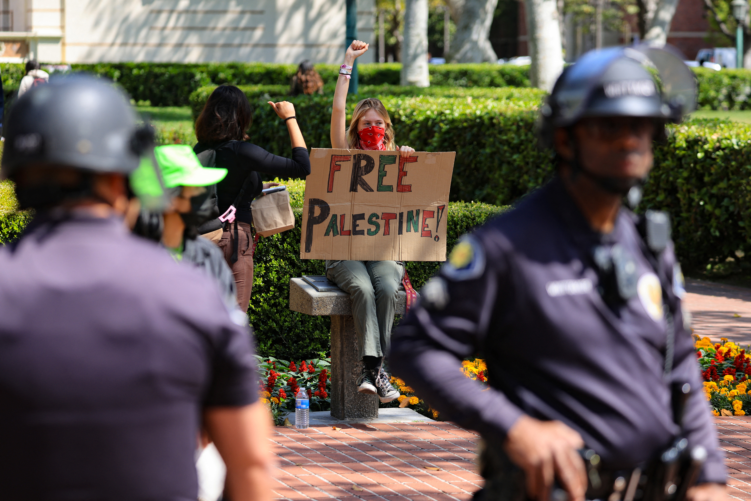 4 月 24 日，在加利福尼亚州洛杉矶的南加州大学校友公园，学生们搭建了支持巴勒斯坦人的抗议营地后，一名举着牌子的示威者举起了拳头。