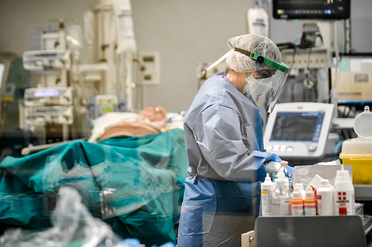 In this photograph taken from behind a window, doctors work on Covid-19 patients in the intensive care unit of San Matteo Hospital, in Pavia, Italy, Thursday, March 26