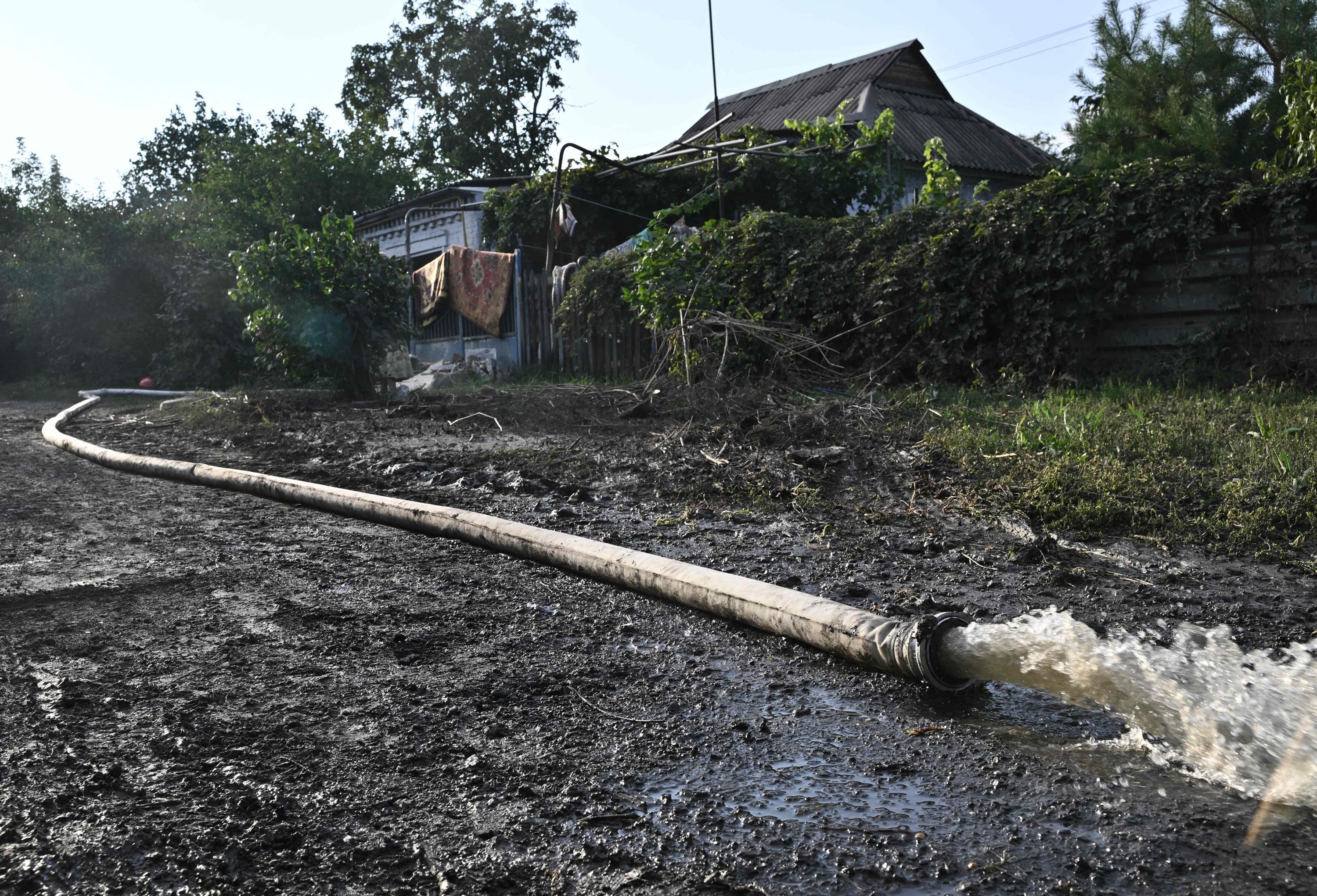 A hose pumps water out from a house in the town of Kryvyi Rih on Friday, where dozens of homes were flooded after a Russian attack damaged a dam upstream.