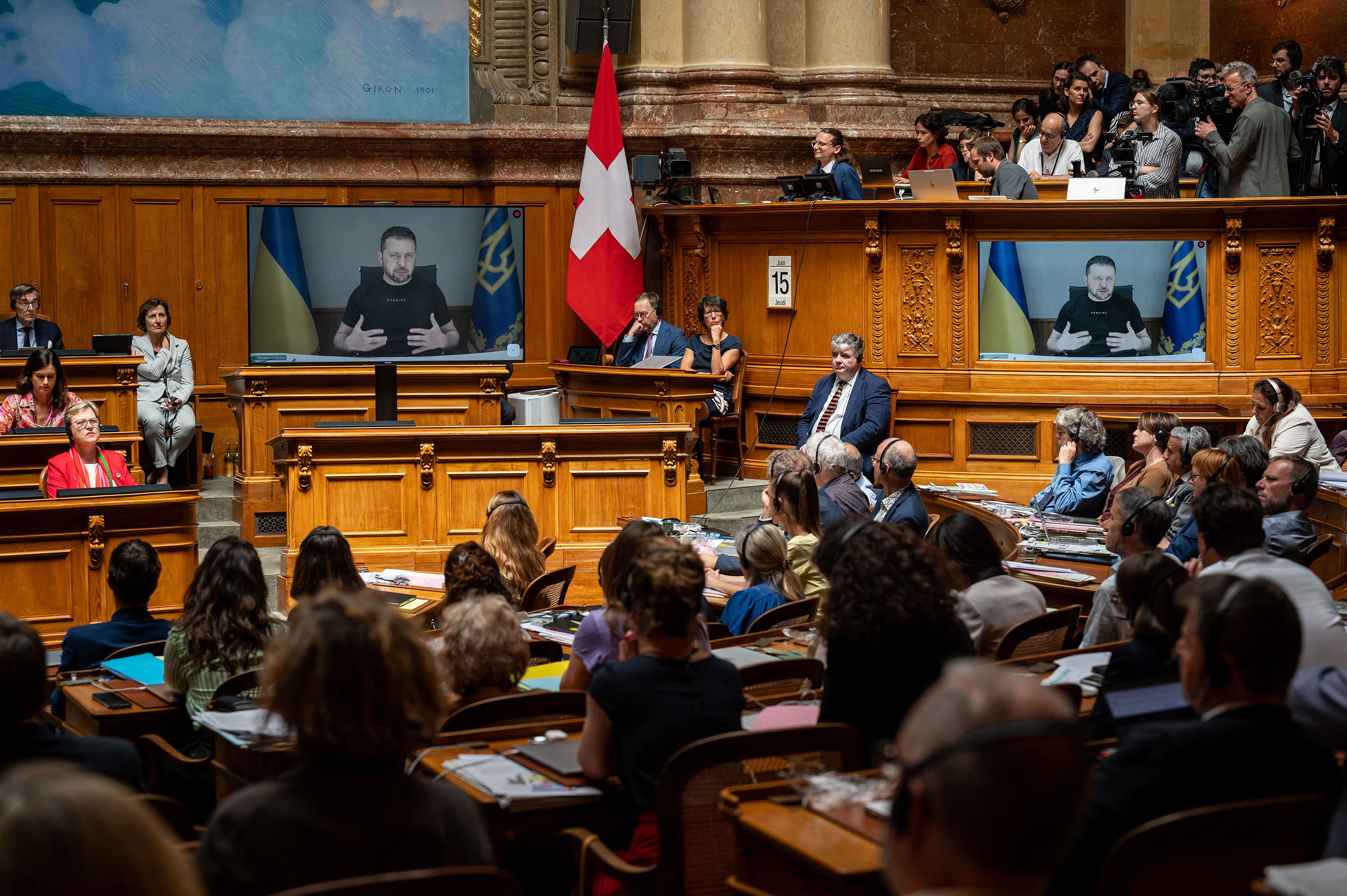 Ukrainian President Volodymyr Zelensky is seen on screens addressing Swiss parliament via video in Bern, Switzerland, on June 15. 