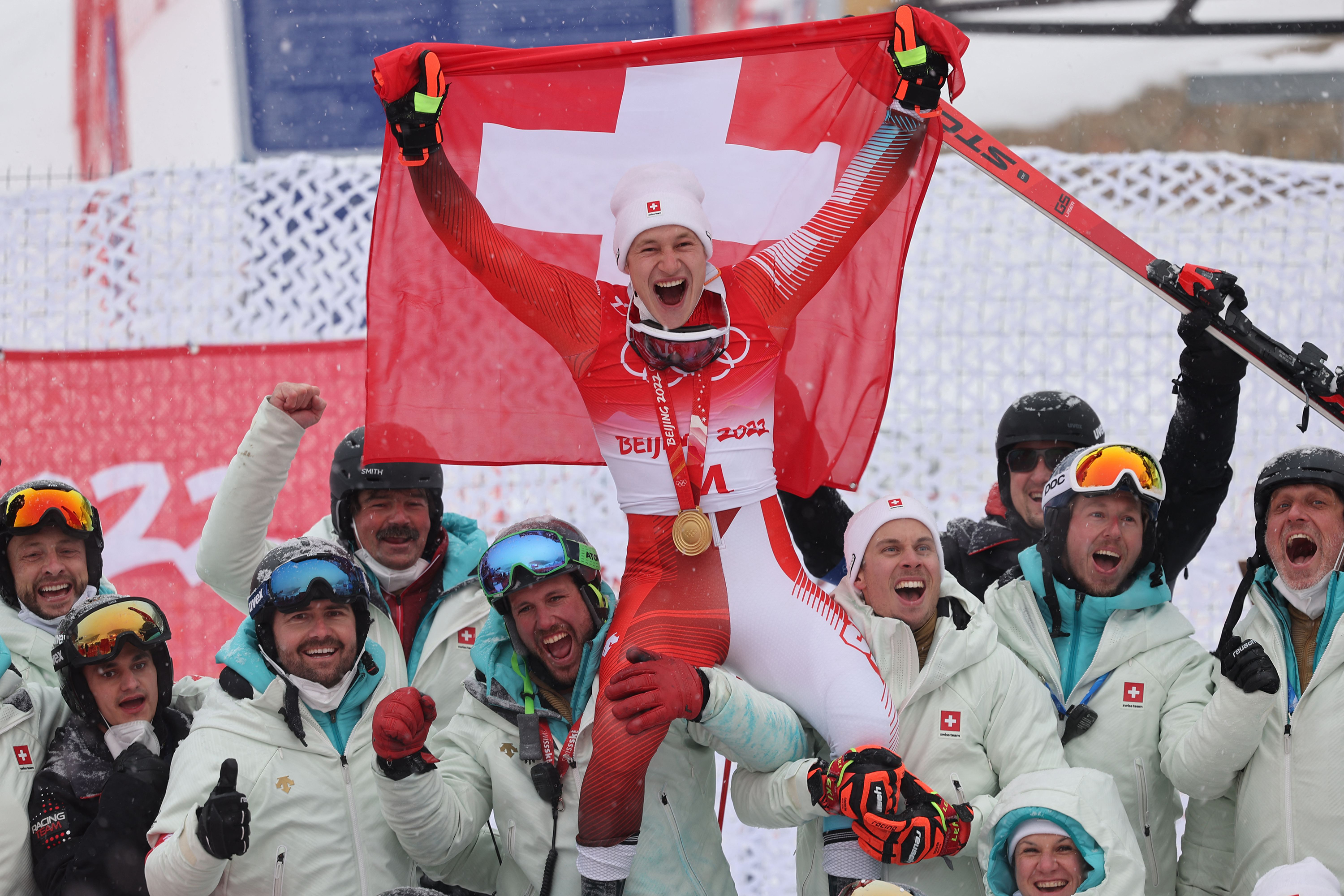 Gold medalist Switzerland's Marco Odermatt (C) celebrates with his team after the men's giant slalom victory ceremony on Sunday.