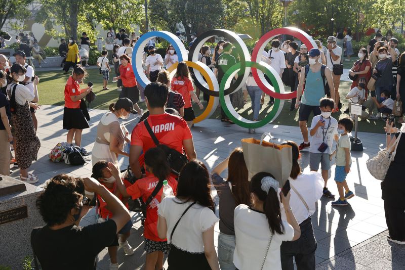 People take photos with the Olympic rings near the National Stadium in Tokyo on Saturday.