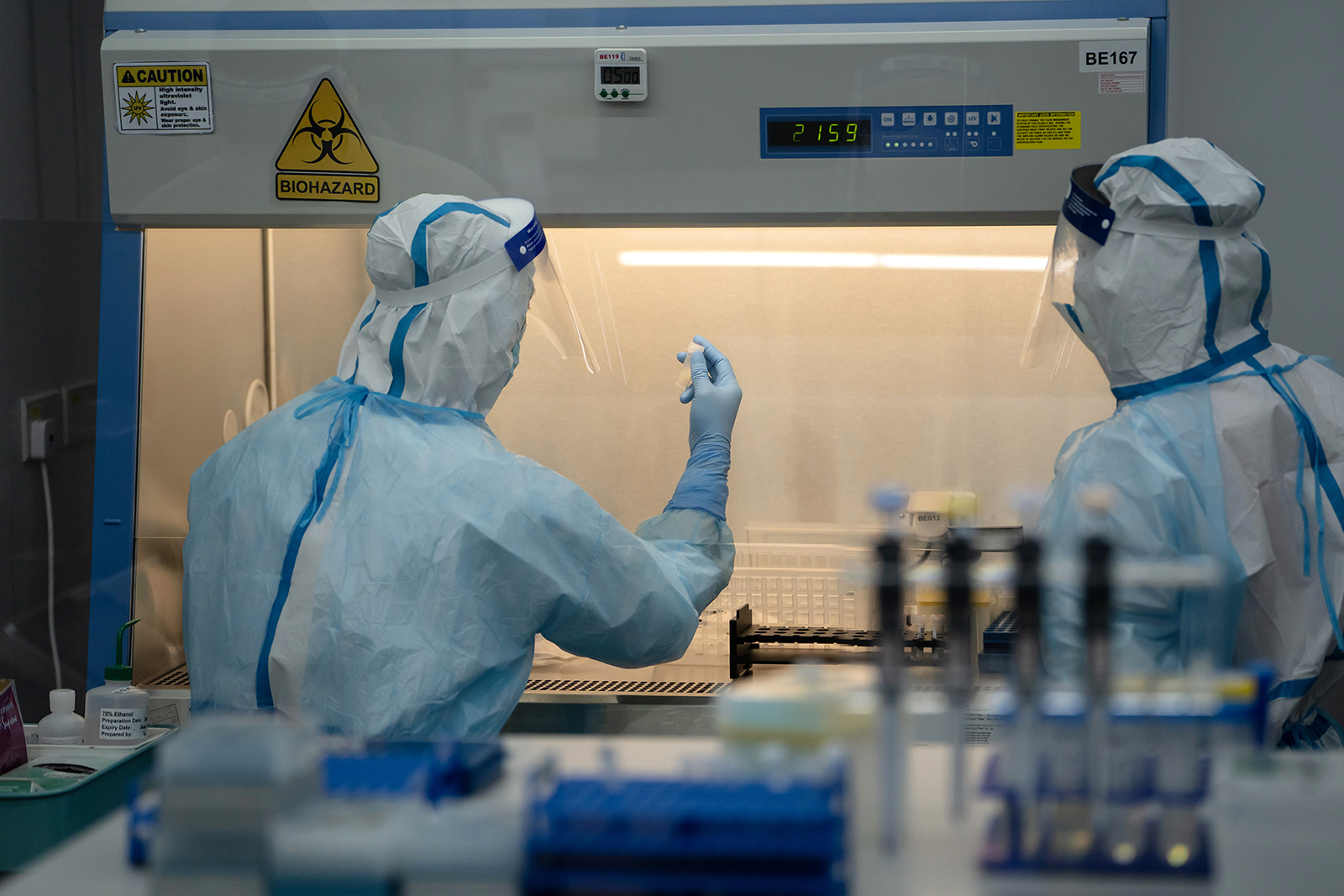 A lab technician wearing a protective suit holds up a saliva sample for RT-PCR Covid-19 testing at Prenetics Ltd.'s laboratory in Hong Kong, China on July 31.