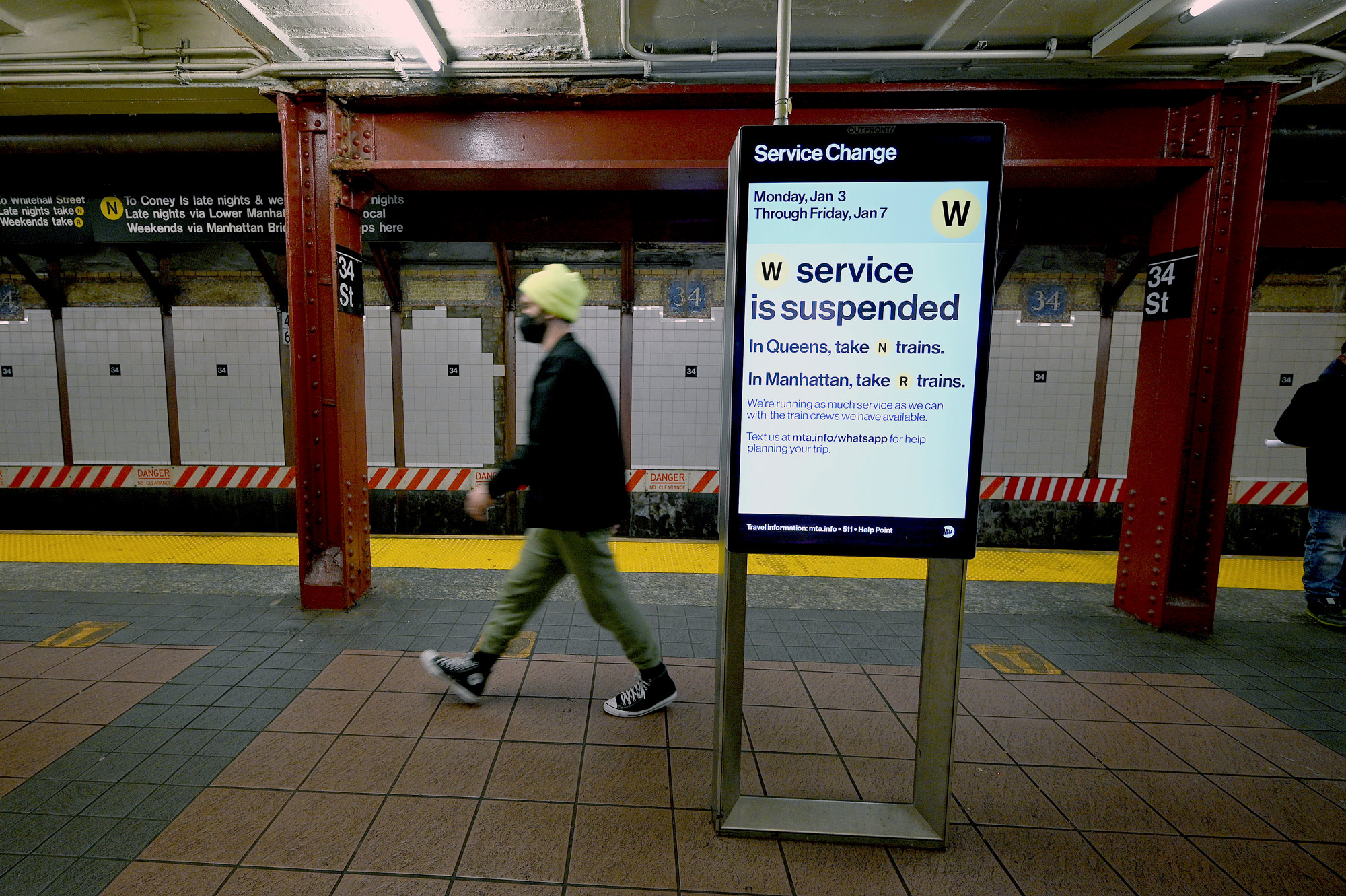 A man walks along a subway platform past an electronic sign announcing that the Metropolitan Transportation Authority suspended the W line due to crew shortage in New York on January 4. 