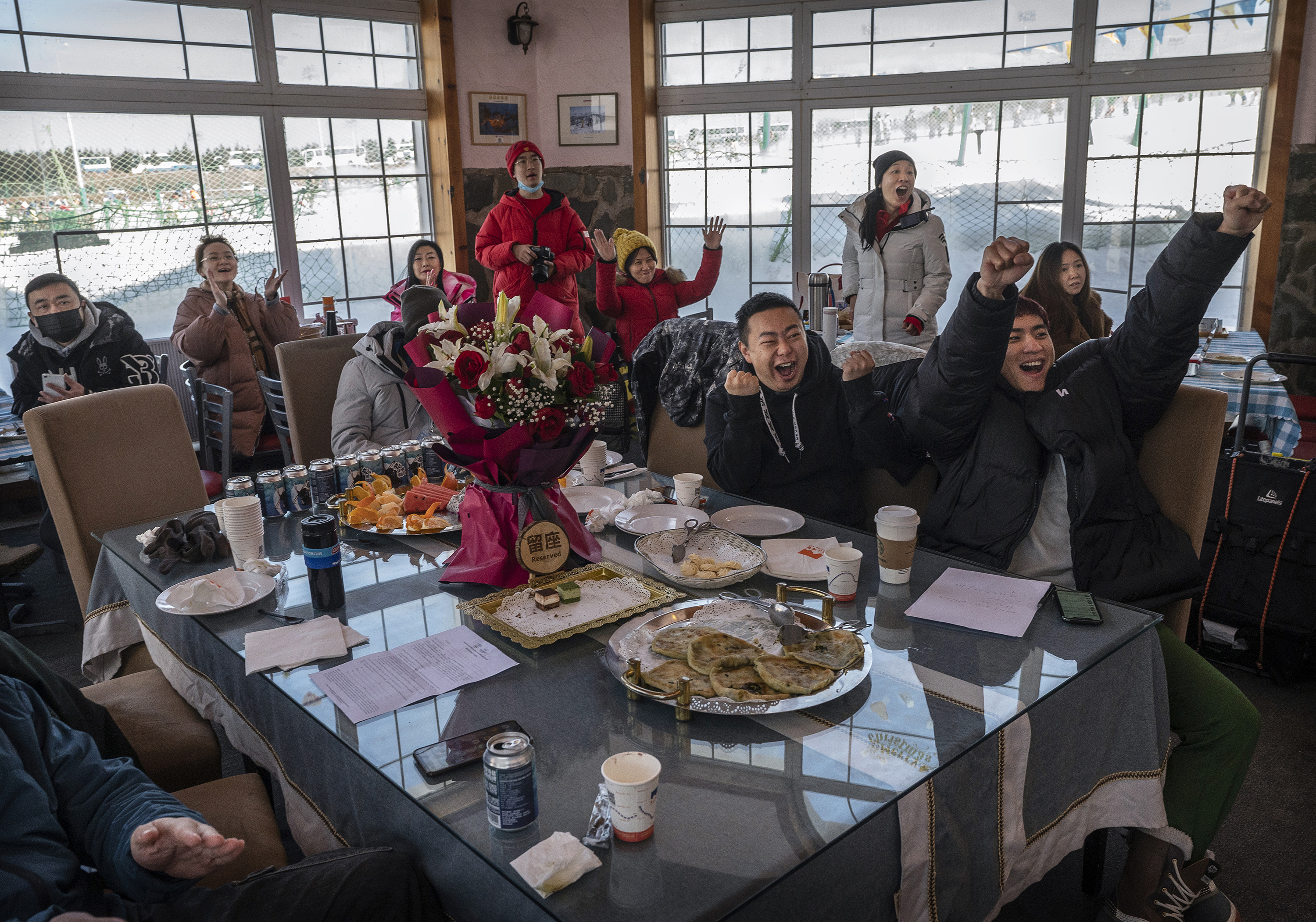 People react as they watch Eileen Gu’s silver medal-winning performance in the slopestyle skiing event on TV on Tuesday in Beijing.