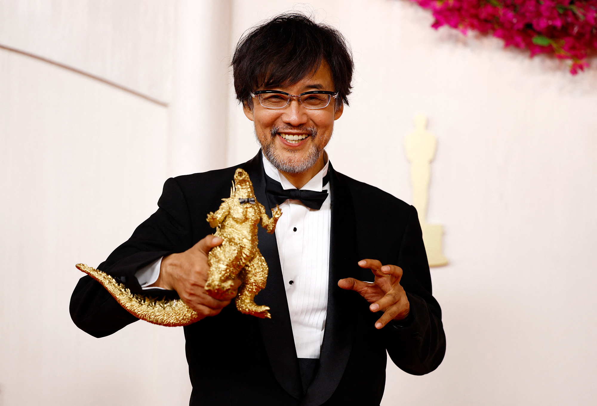 Takashi Yamazaki poses with a Godzilla figure on the red carpet. 