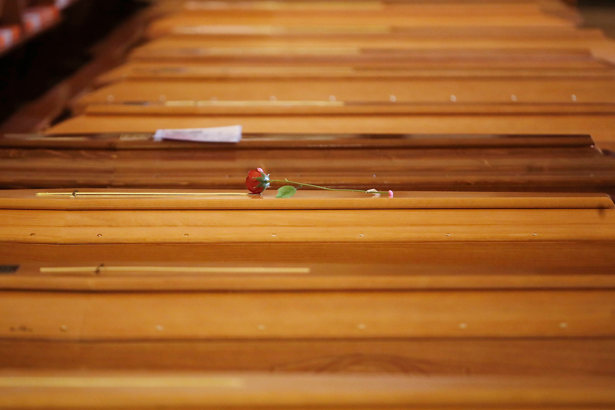 A red rose lies on a coffin lined up along others inside the San Giuseppe church in Seriate, Italy, on Saturday, March 28.