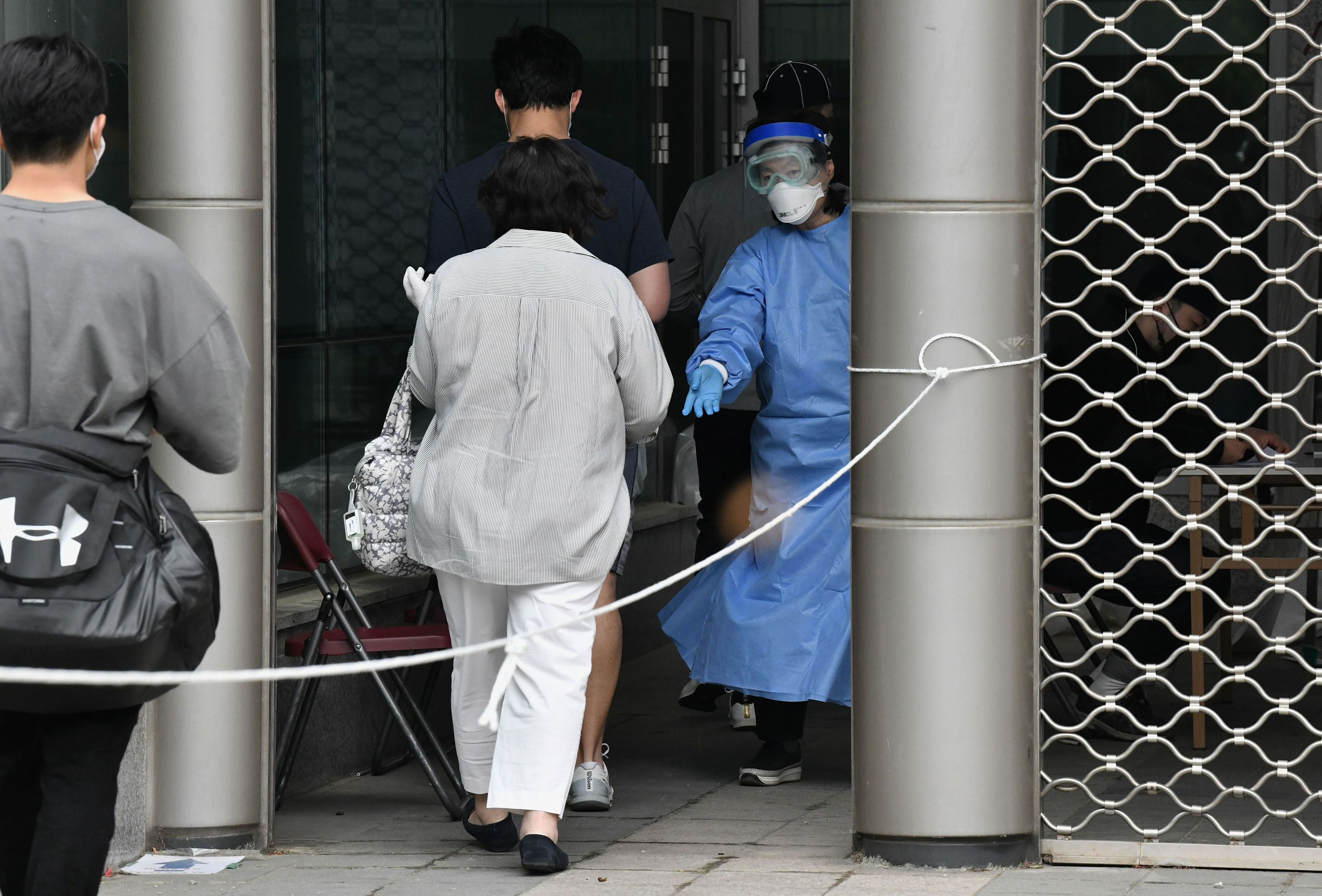 A medical staff member wearing personal protective equipment (PPE) guides visitors for COVID-19 testing at a testing station in the nightlife district of Itaewon in Seoul, Korea, on Tuesday, May 12.