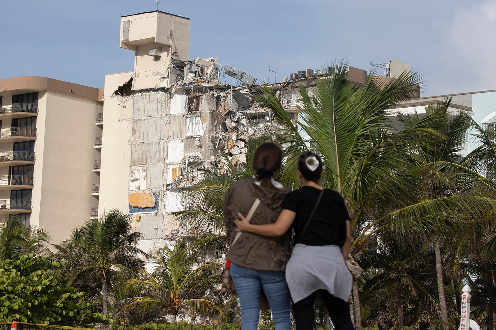 Maria Fernanda Martinez and Mariana Cordeiro look on as search and rescue operations continue at the site of the partially collapsed 12-story Champlain Towers South condo building on Friday in Surfside.