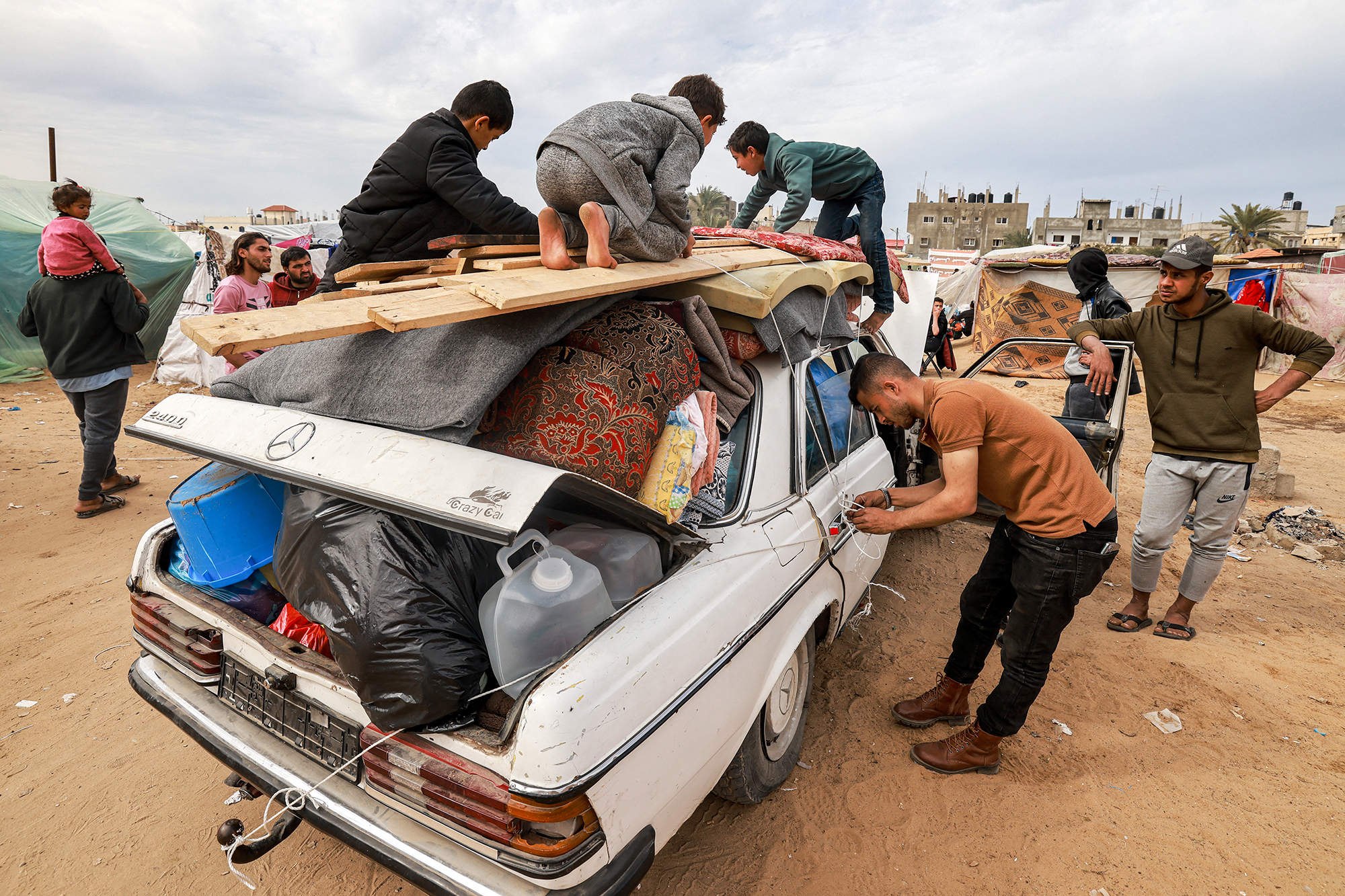A man ties up a rope securing items onto a vehicle as members of a Palestinian family flee from Rafah, Gaza, on February 13.