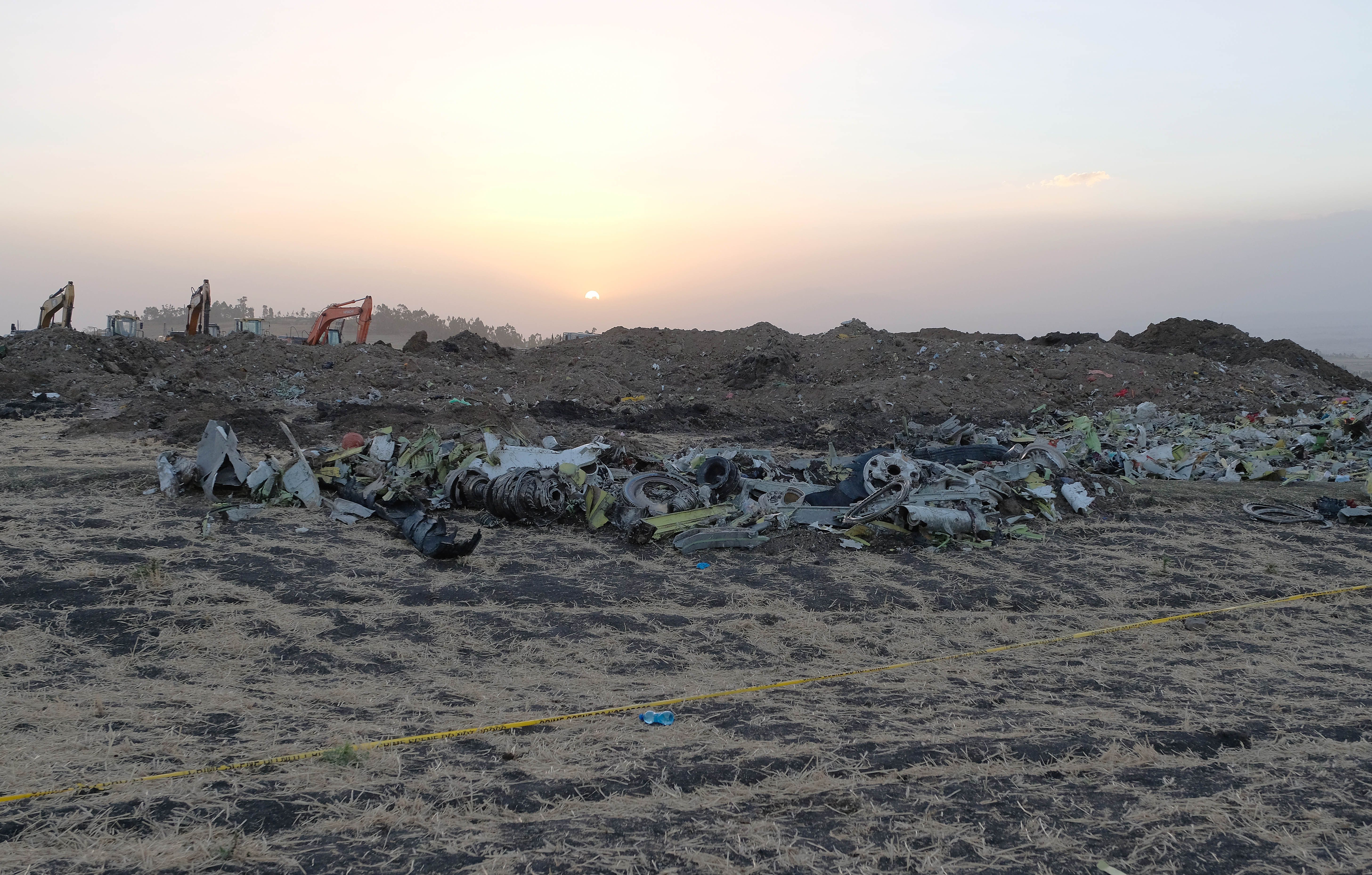Debris lays piled up just outside the impact crater after being gathered by workers during the continuing recovery efforts at the crash site of Ethiopian Airlines flight ET302.