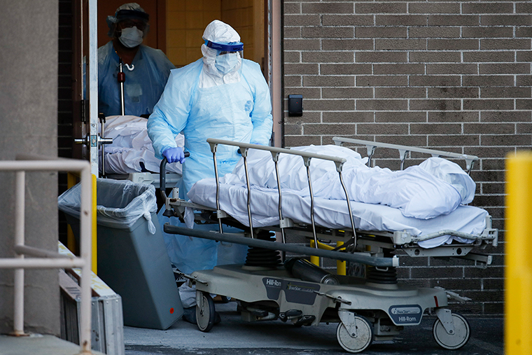 A medical worker moves a body to a refrigerated trailer serving as a makeshift morgue at Wyckoff Heights Medical Center, Monday, April 6, in New York. 