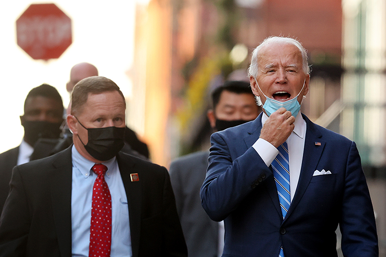 US President-elect Joe Biden pulls down his face mask as he talks with reporters as he leaves the Queen Theater on Monday, December 07, in Wilmington, Delaware. 