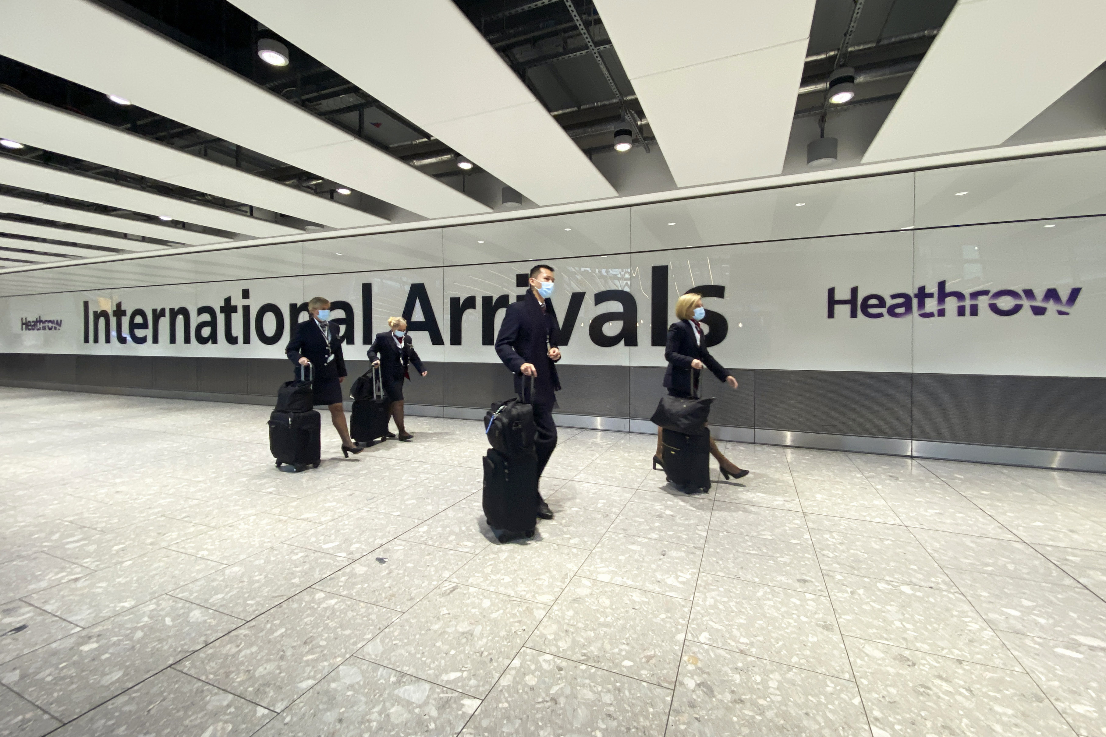 Members of a cabin crew walk through International Arrivals, at London's Heathrow Airport, Friday, Nov. 26, 2021. The U.K. announced that it was banning flights from South Africa and five other southern African countries effective at noon on Friday, and that anyone who had recently arrived from those countries would be asked to take a coronavirus test.