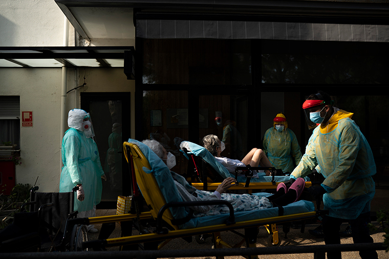 Health workers carry on a stretcher two elderly residents of a nursing home who tested positive for the new coronavirus in Barcelona, Spain, Saturday, April 1. 