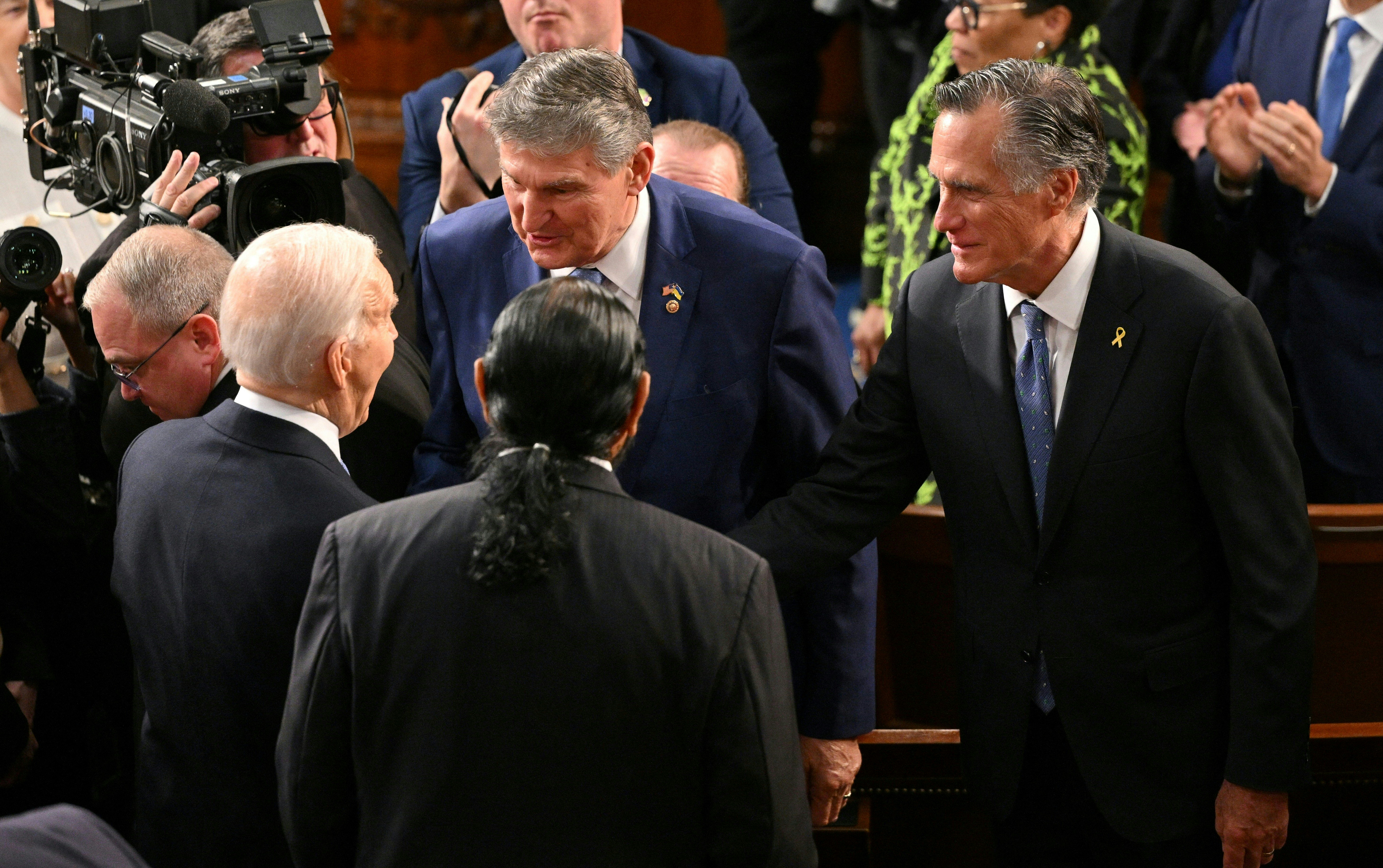 President Joe Biden speaks with Sen. Mitt Romney, right, and Sen. Joe Manchin as he arrives to deliver the State of the Union address.