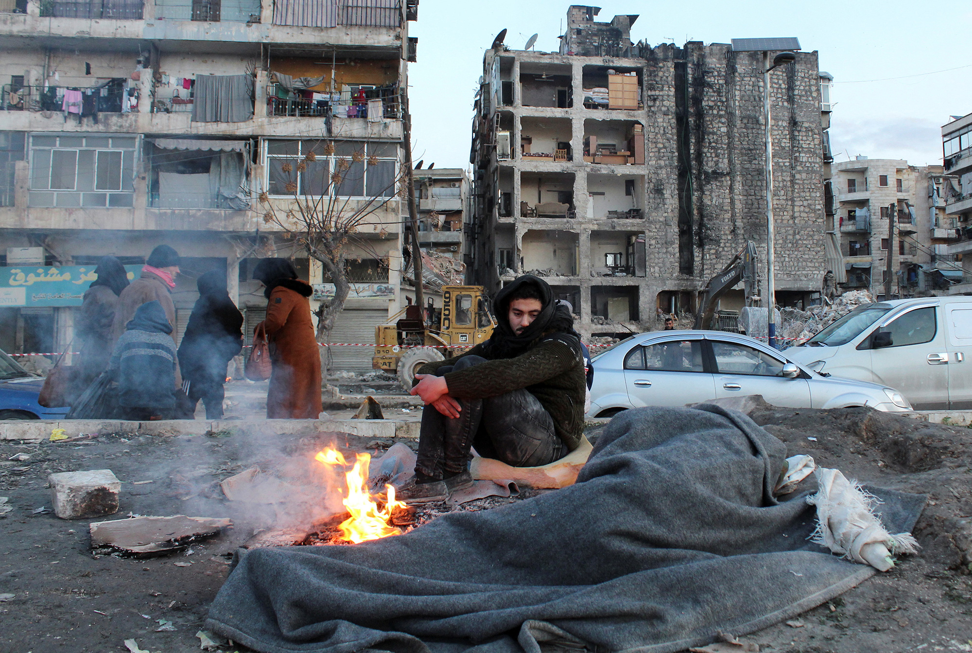 A man who evacuated his home warms up by a fire in the street after the earthquake in Aleppo, Syria, on February 8.