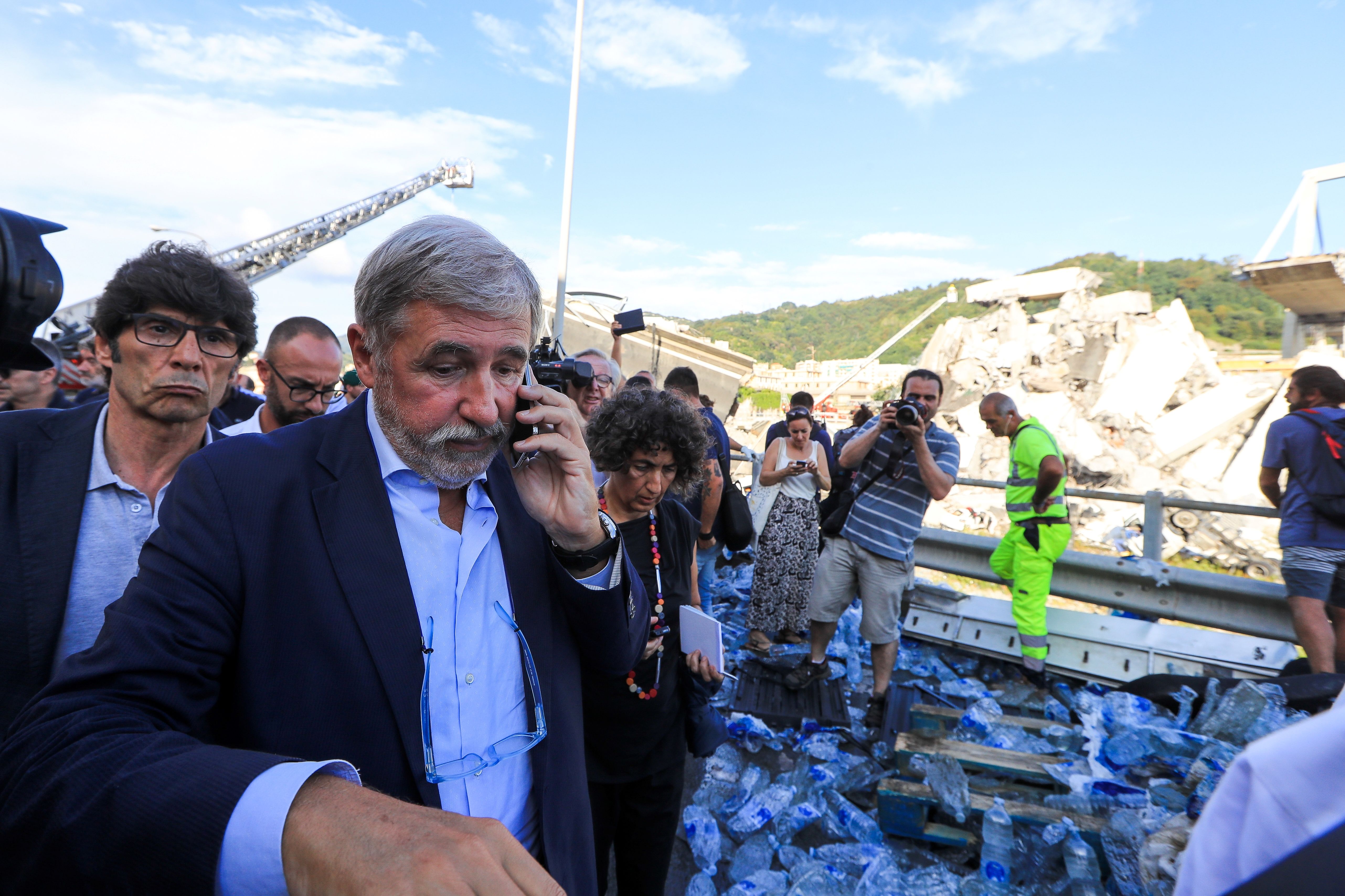 Mayor of Genoa Marco Bucci speaks on a mobile as he walks at the site where the Morandi bridge collapsed 