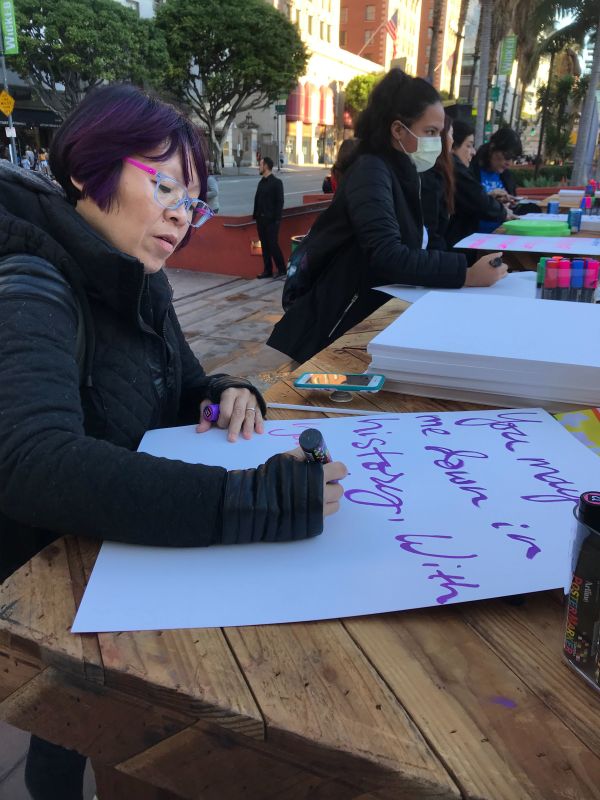 Yanti Palleschi makes a sign ahead of the women's march in Los Angeles.