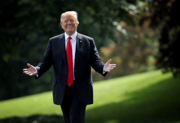 Trump gestures toward journalists shouting questions as he departs the White House May 29