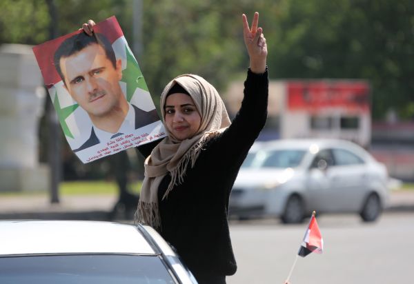A Syrian woman carries a portrait of President Bashar al-Assad as makes her way to Umayyad Square in Damascus on Saturday to condemn the strikes carried out by the US, Britain and France against the Syrian regime. 