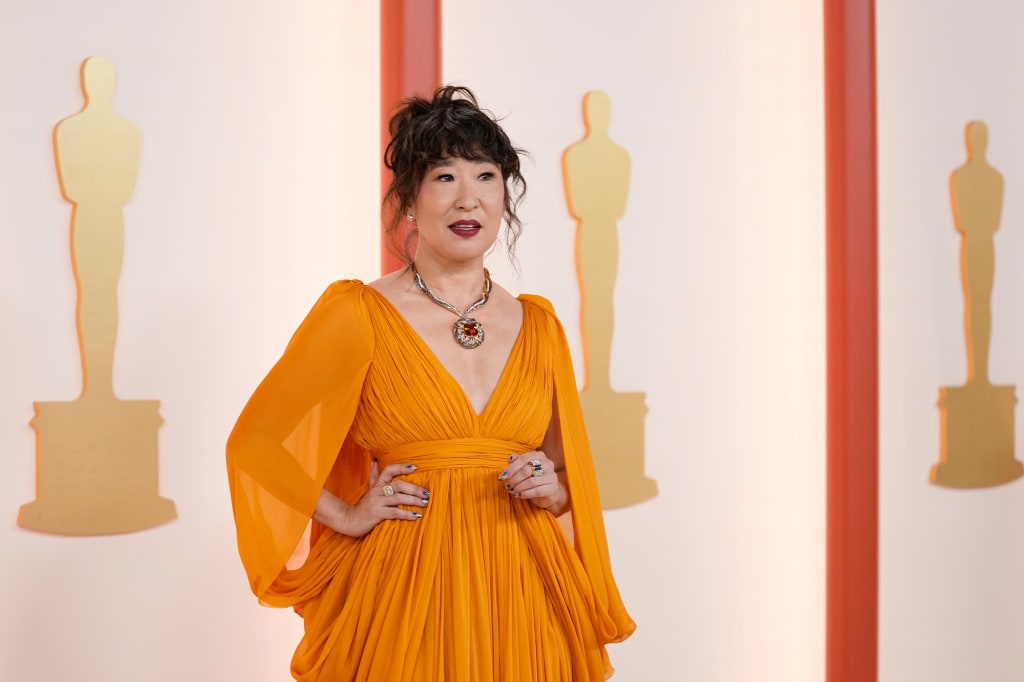 Sandra Oh mori pjesë e veshur me një fustan tërheqës me marigold nga koleksioni Pranverë-Verë 2023 i Giambattista Valli Haute Couture.