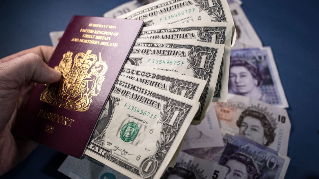  UK passport is seen besides US Dollar bills and Pound Sterling notes 