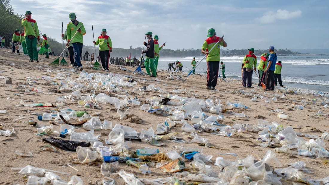 Workers clean up piles of debris and plastic waste brought in by strong waves at Kuta Beach in Bali, Indonesia, 01 January 2021.