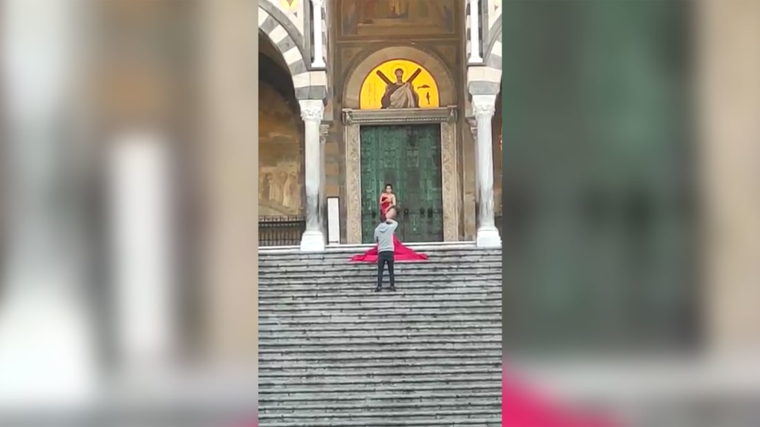 The woman stripped off on the top of the steps and posed for photos covered in a red material.