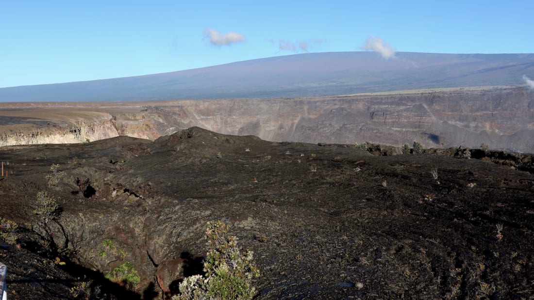 Hawaii's Mauna Loa volcano, in the background, towers over the summit crater of Kilauea volcano in Hawaii Volcanoes National Park on the Big Island on April 25, 2019.
