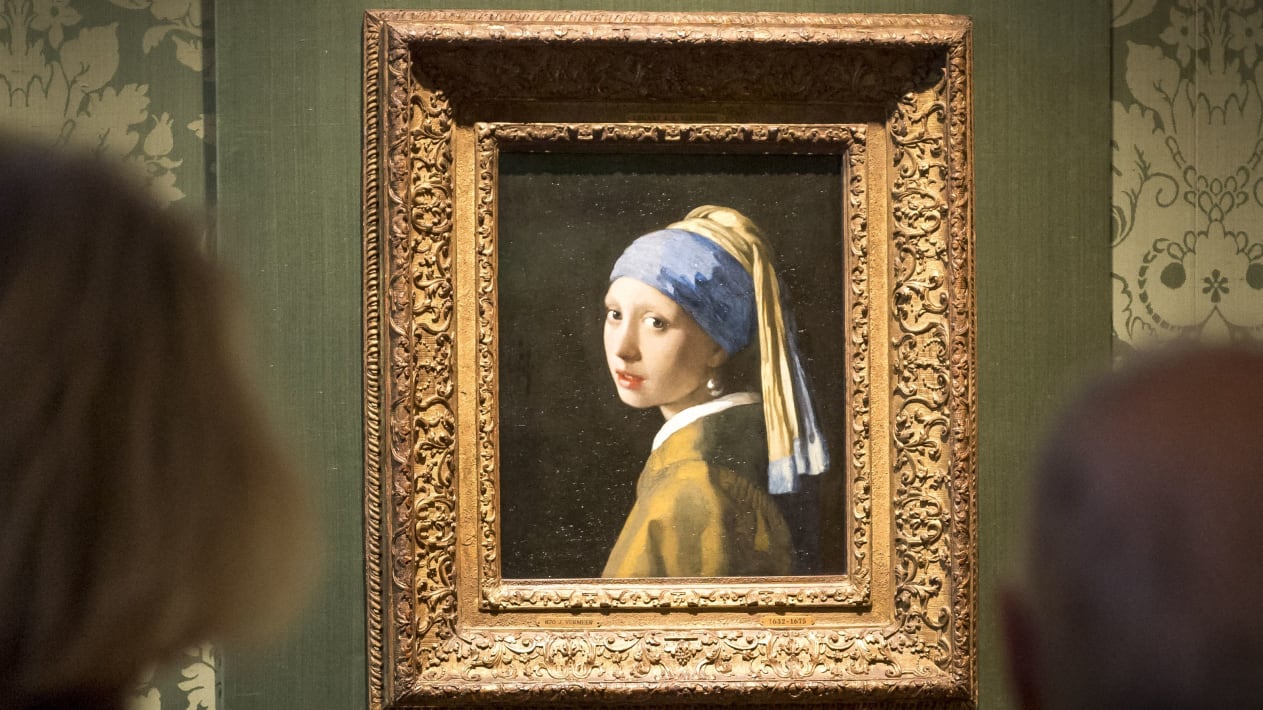 Vizitorët shikojnë pikturën e Johannes Vermeer "Vajza me një vath perl" në muzeun Mauritshuis në Hagë, 27 tetor 2022. - Policia holandeze arrestoi tre persona pasi aktivistët e klimës shënjestruan pikturën e Johannes Vermeer "Vajza me një vath perle". - Netherlands OUT (Foto nga Lex van Lieshout / ANP / AFP) / Holanda OUT (Foto nga LEX VAN LIESHOUT/ANP/AFP nëpërmjet Getty Images)