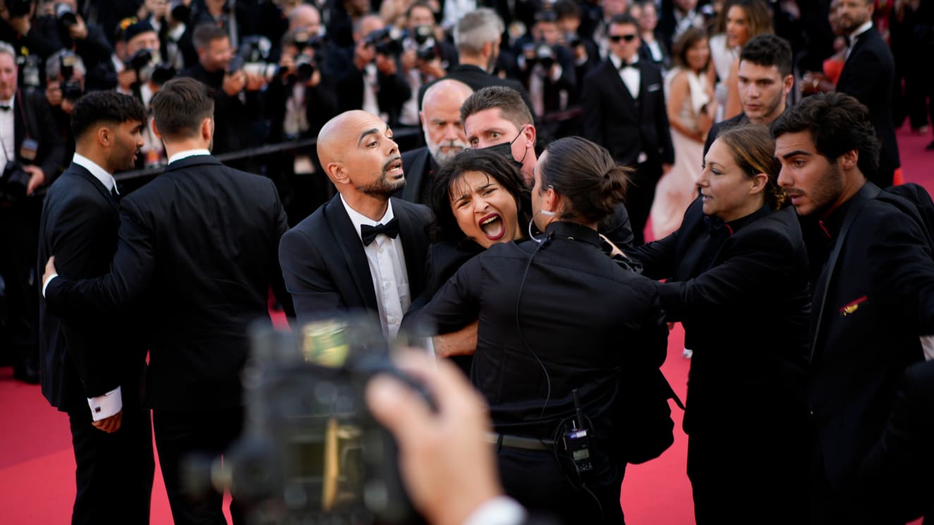 A protestor wearing body paint that reads "Stop Raping Us" in the color of the Ukrainian flag is removed from the Cannes red carpet