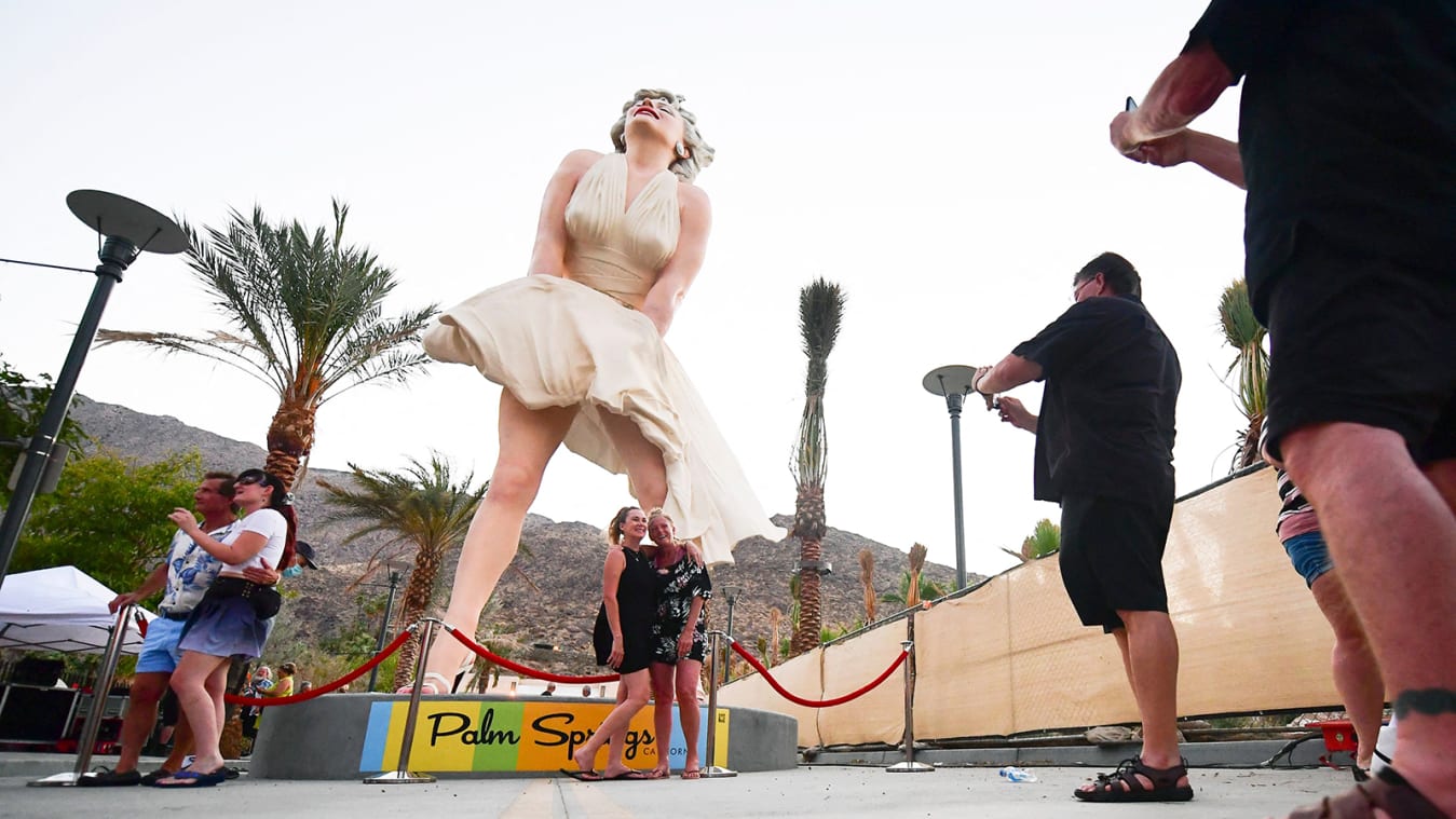 People visit the "Forever Marilyn" statue unveiled today on its return to Palm Springs, California on June 20, 2021. - The 26-foot tall and 17-ton sculpture by artist Seward Johnson Atelier was displayed earlier this decade in Palm Springs, but the return has drawn the ire of residents on infringement of surrounding natural landscape views and on allegations the statue is sexist and innapropriate, despite the popularity of Marilyn Monroe's iconic dress-flying pose from the 1955 comedy "The Seevn Year Itch." - RESTRICTED TO EDITORIAL USE - MANDATORY MENTION OF THE ARTIST UPON PUBLICATION - TO ILLUSTRATE THE EVENT AS SPECIFIED IN THE CAPTION (Photo by Frederic J. BROWN / AFP) / RESTRICTED TO EDITORIAL USE - MANDATORY MENTION OF THE ARTIST UPON PUBLICATION - TO ILLUSTRATE THE EVENT AS SPECIFIED IN THE CAPTION / RESTRICTED TO EDITORIAL USE - MANDATORY MENTION OF THE ARTIST UPON PUBLICATION - TO ILLUSTRATE THE EVENT AS SPECIFIED IN THE CAPTION (Photo by FREDERIC J. BROWN/AFP via Getty Images)